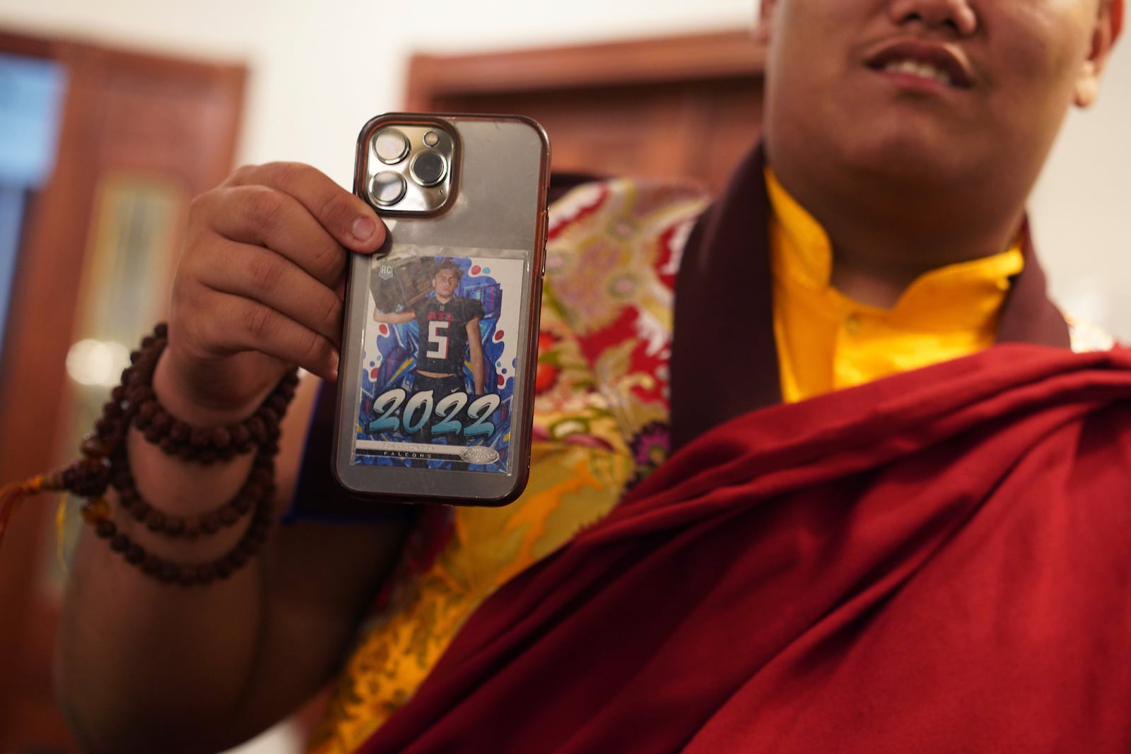 U.S.-born Buddhist lama, Jalue Dorje, shows his Drake London, Atlanta Falcons, rookie card, which sits in the back of his phone, at his 18th birthday and enthronement ceremony at the Tibetan American Foundation of Minnesota, on Saturday, Nov. 9, 2024, in Isanti, Minn. (AP Photo/Jessie Wardarski)