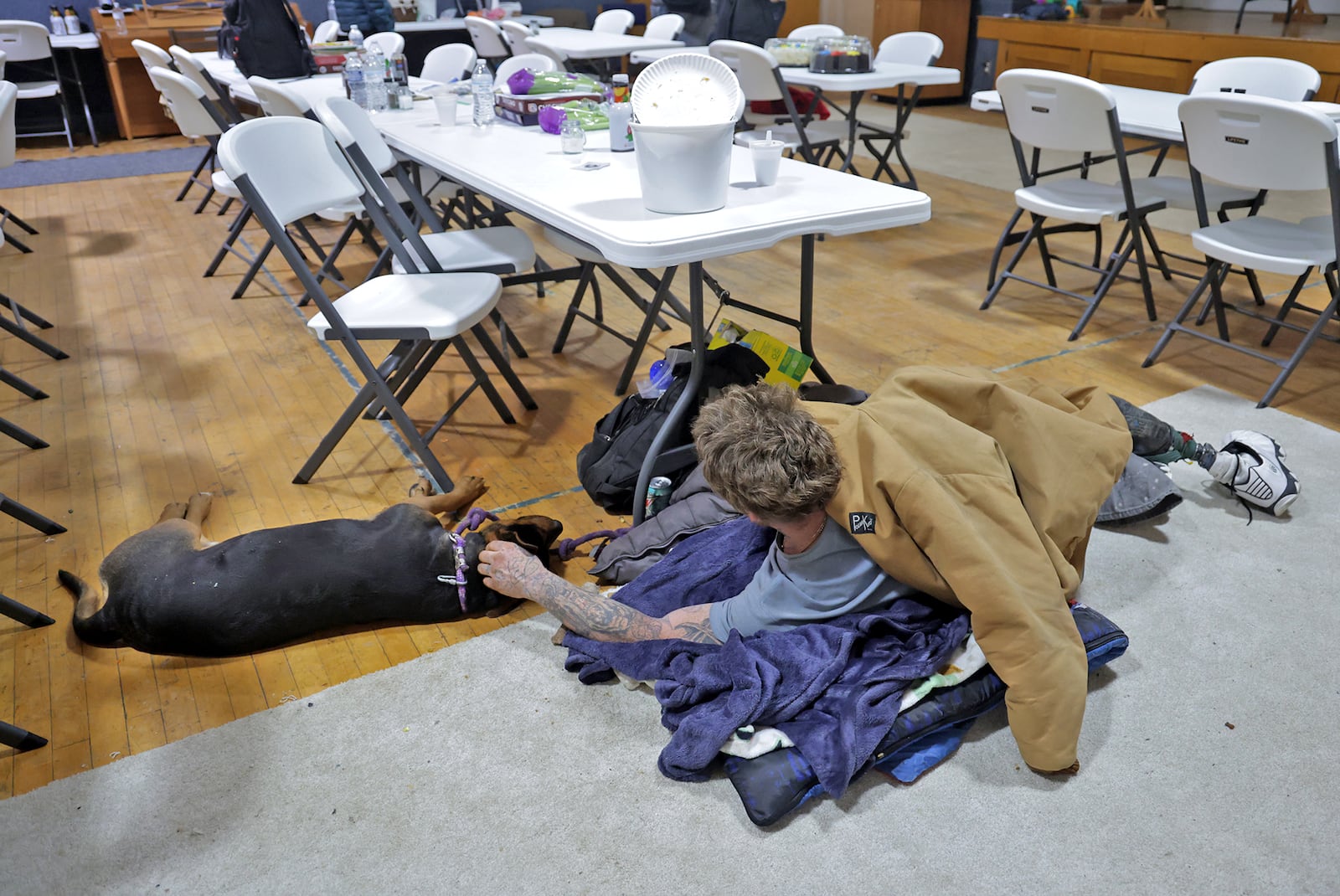 A homeless man pets his dog as they relax on the floor in the Springfield Warming Center. BILL LACKEY/STAFF