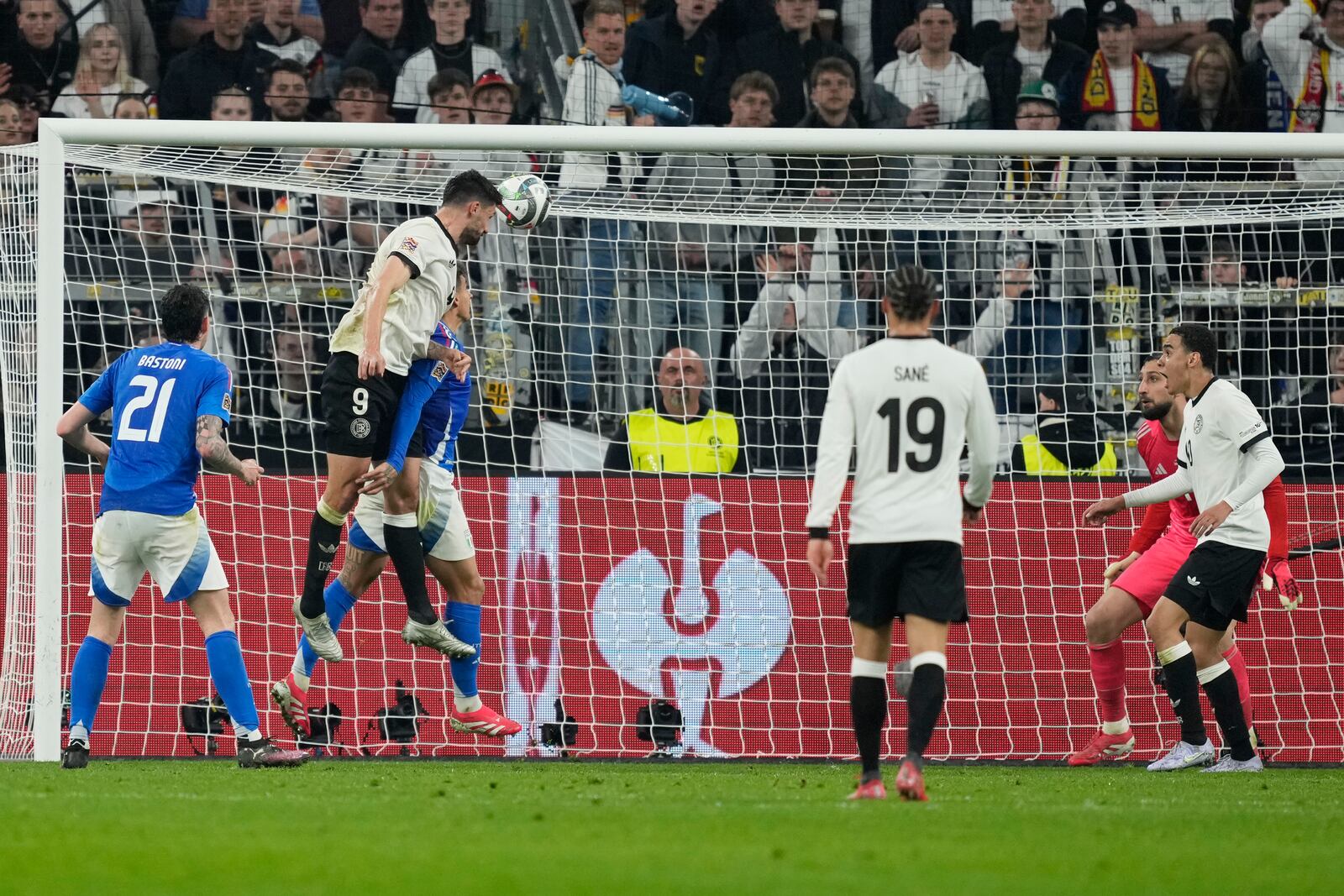 Germany's Tim Kleindienst, top, scores his side's third goal during the Nations League quarterfinal second leg soccer match between Germany and Italy at the Signal-Iduna Park in Dortmund, Germany, Sunday, March 23, 2025. (AP Photo/Martin Meissner)