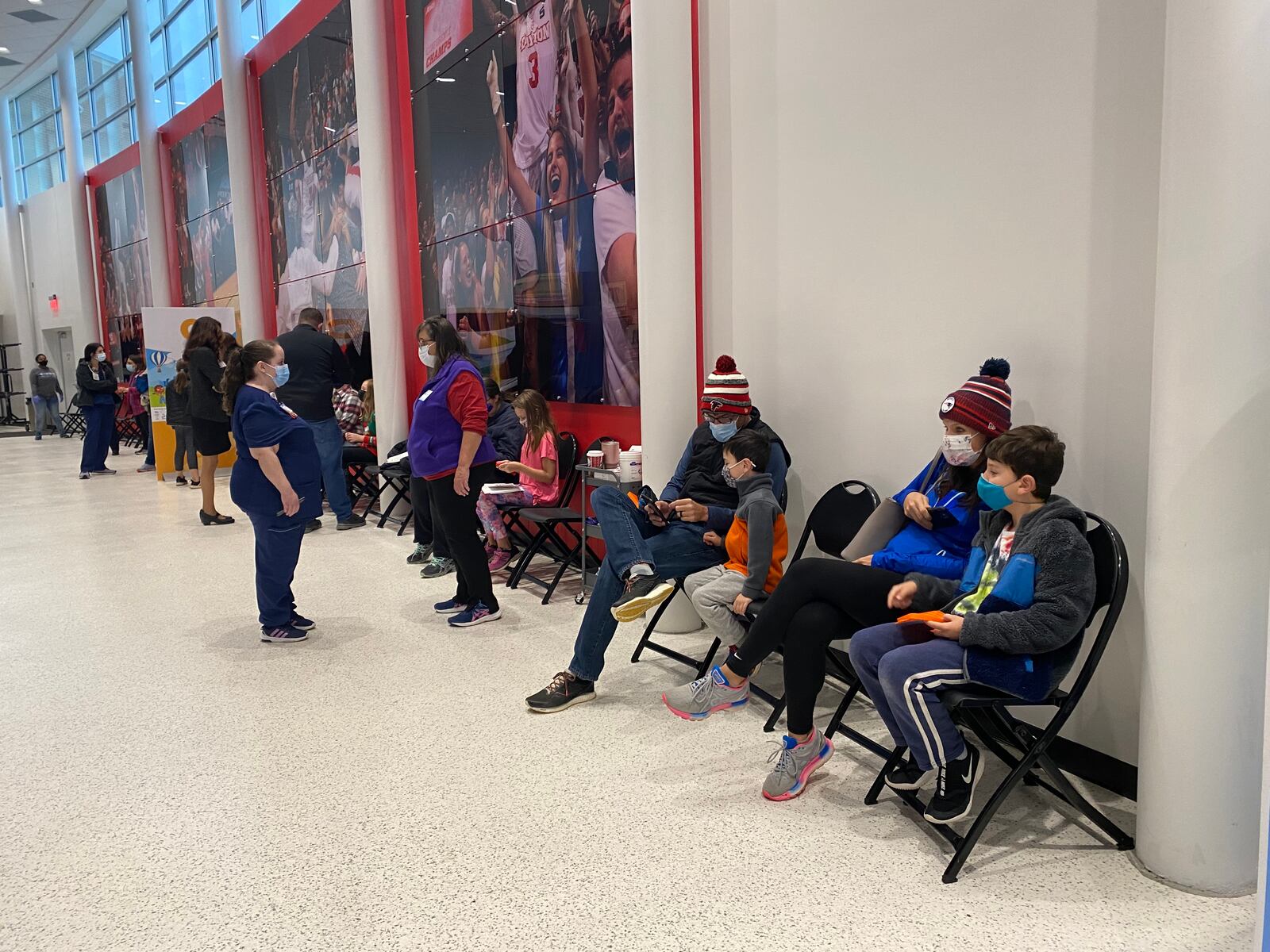 Families and staff wait in the hallway at UD Arena for a 15 minute observation period on Sunday after getting the vaccine. Eileen McClory / staff