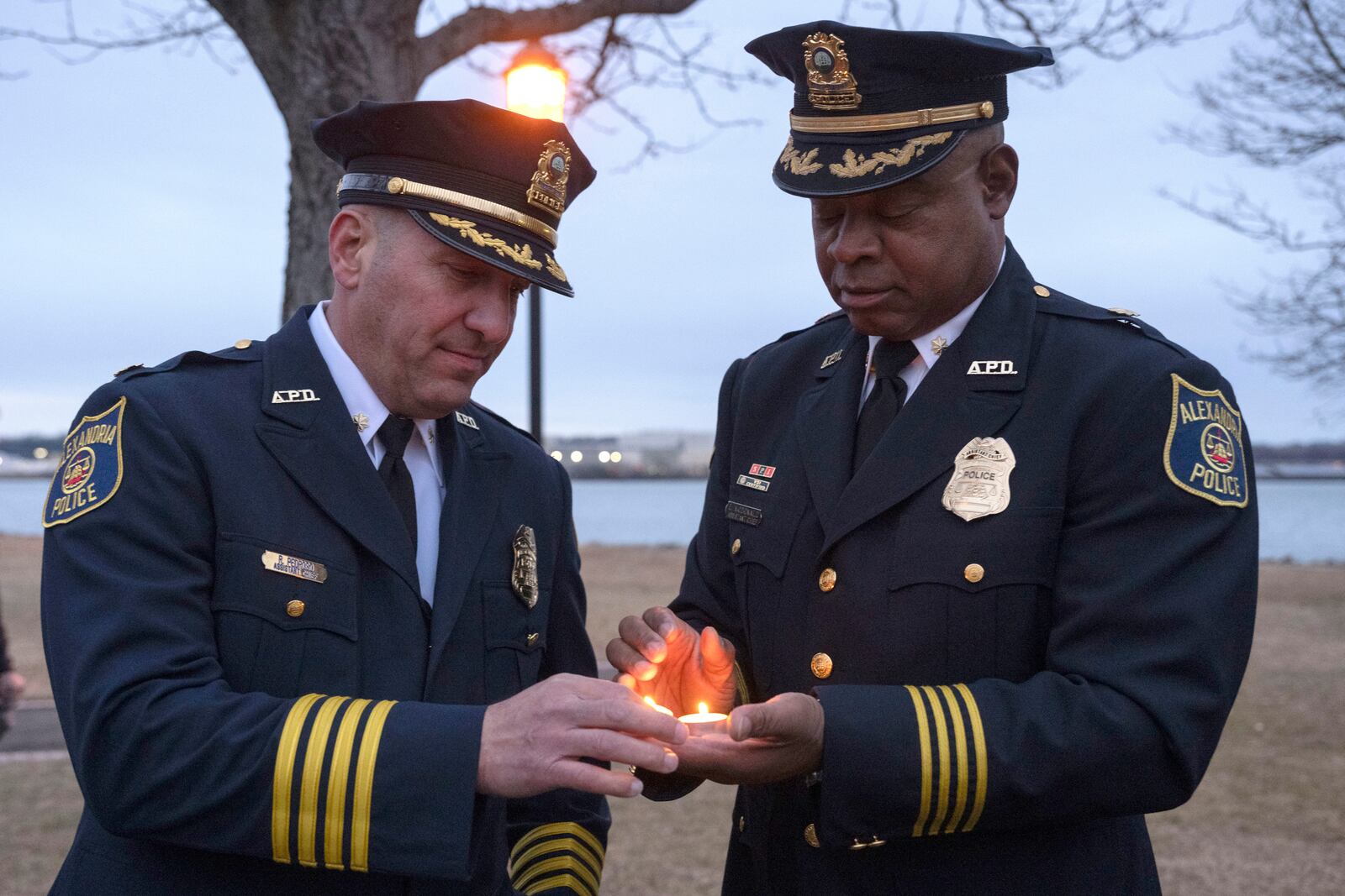 Assistant Police Chief for the City of Alexandria Easton McDonald, right, shares a candle with fellow Assistant Chief Raul Pedroso at the start of a candlelight vigil, Wednesday, Feb. 5, 2025 in Alexandria, Va., for the victims of the mid-air collision of an American Airlines jet and a Black Hawk helicopter at Reagan National Airport. (AP Photo/Kevin Wolf)