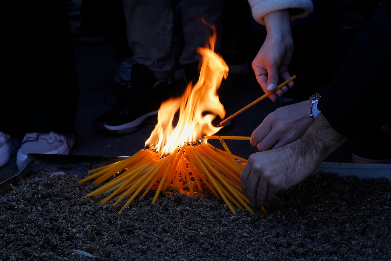 University students light candles for the victims of a massive nightclub fire in the town of Kocani, in Skopje, North Macedonia, Tuesday, March 18, 2025. (AP Photo/Boris Grdanoski)