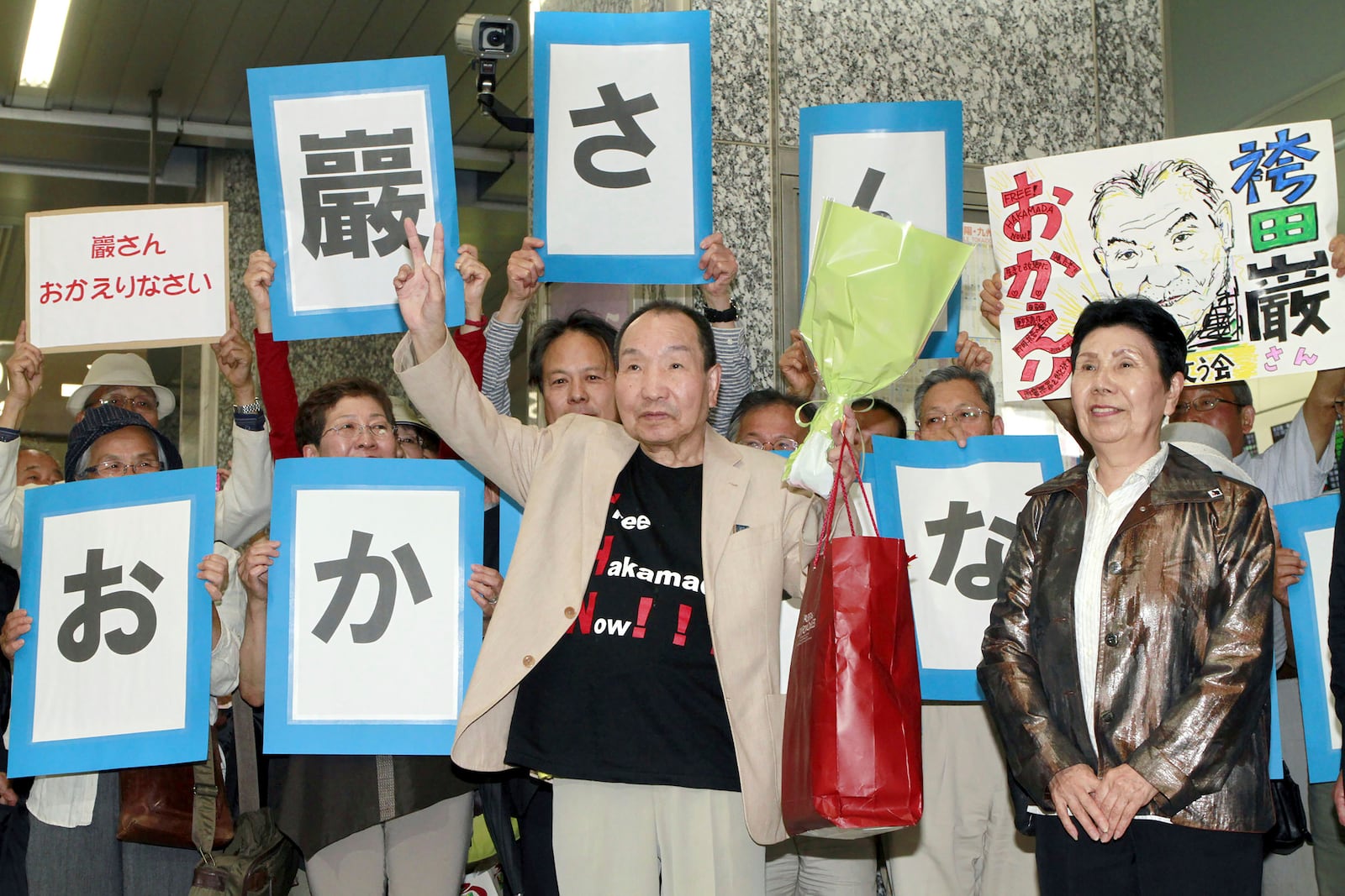 Iwao Hakamada, center, who has been sentenced to death in a 1966 quadruple murder case, with his sister Hideko Hakamada, right, is welcomed by supporters on his arrival at Hamamatsu, Shizuoka prefecture, central Japan, on May 27, 2014. Japanese prosecutors said on Oct. 8, 2024 they will not appeal the Sept. 26 ruling of the Shizuoka District Court that acquitted the world’s longest-serving death-row inmate in a retrial. The signs read "Welcome back, Iwao." (Kyodo News via AP)