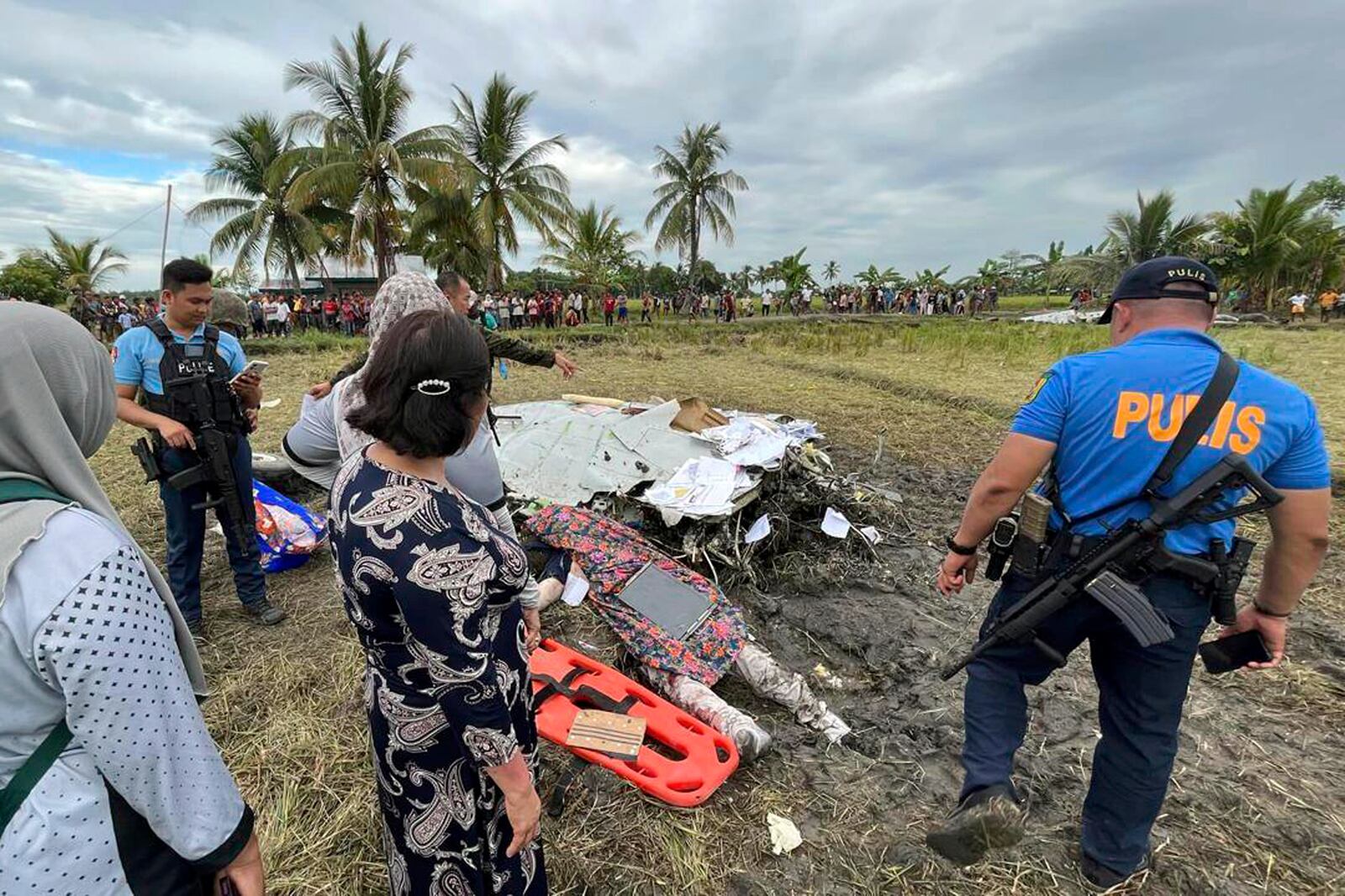 The body of a victim is covered with a blanket as police officers inspect the site where wreckage of airplane is seen in a rice field in Maguindanao del Sur province, Philippines, after officials say a U.S. military-contracted plane has crashed in a rice field in the southern Philippines, killing all four people on board, on Thursday Feb. 6, 2025. (Sam Mala/UGC via AP)