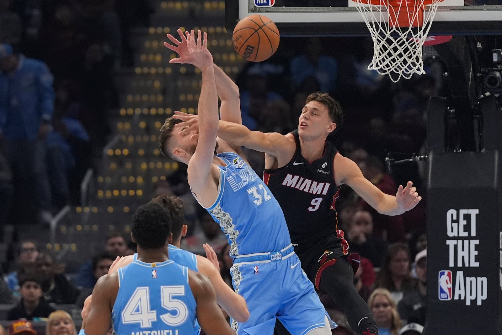 Miami Heat guard Pelle Larsson (9) fouls Cleveland Cavaliers forward Dean Wade (32) in the first half of an NBA basketball game Wednesday, March 5, 2025, in Cleveland. (AP Photo/Sue Ogrocki)