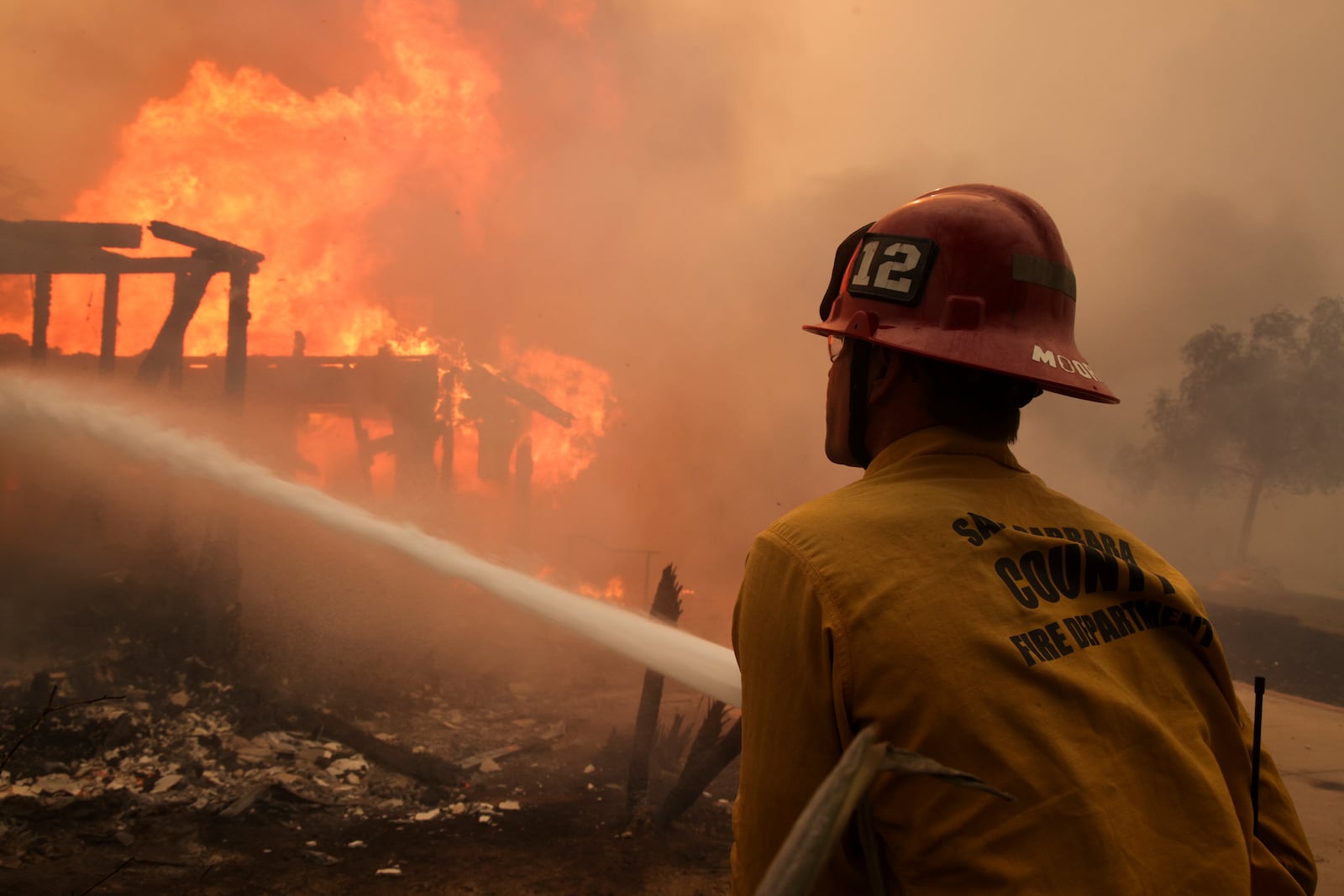 Firefighters spray water on a burning structure during the Mountain Fire, Wednesday, Nov. 6, 2024, near Camarillo, Calif. (AP Photo/Ethan Swope)