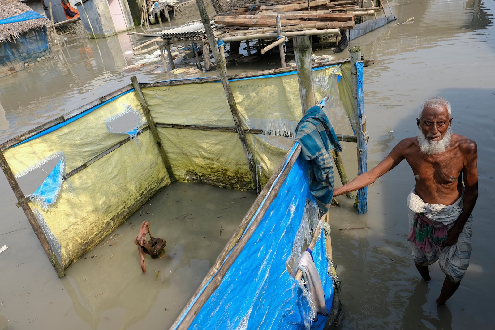 FILE - An elderly man stands by a tube well buried in water during high tide in Pratap Nagar, in Shyamnagar region of Satkhira district, Bangladesh on Oct. 5, 2021. (AP Photo/Mahmud Hossain Opu, File)