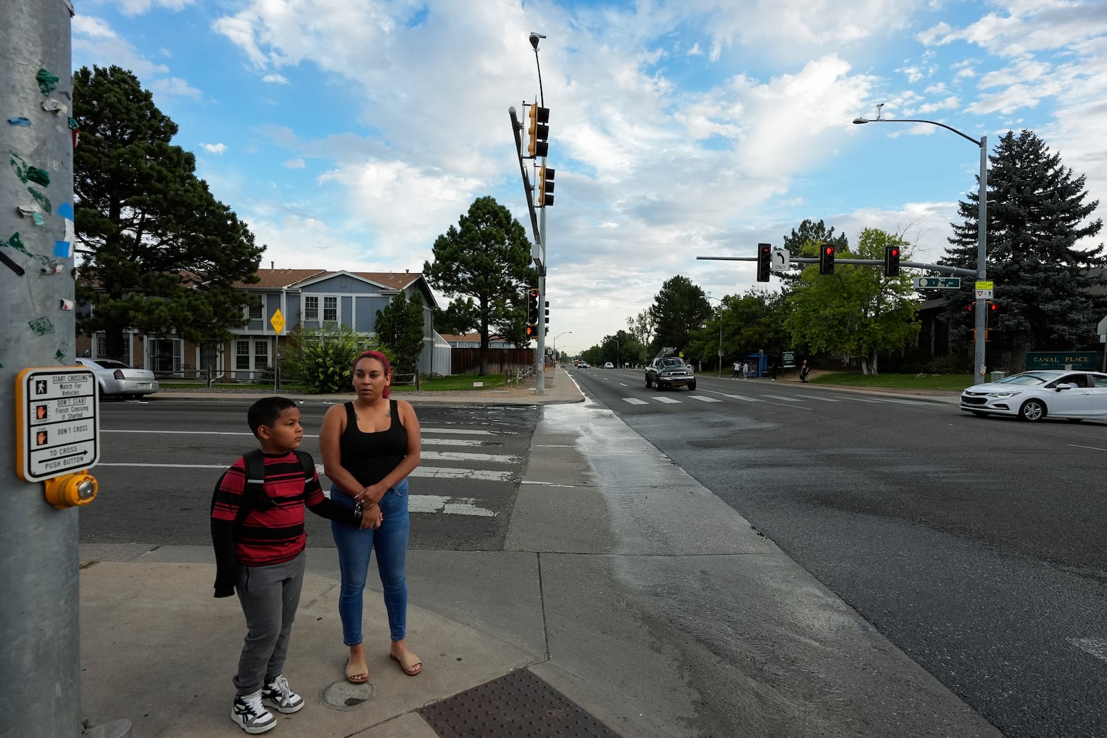 Gabriela Ramírez and her son Dylan wait for the pedestrian signal to cross an intersection on their way to school Thursday, Aug. 29, 2024, in Aurora, Colo. (AP Photo/Godofredo A. Vásquez)