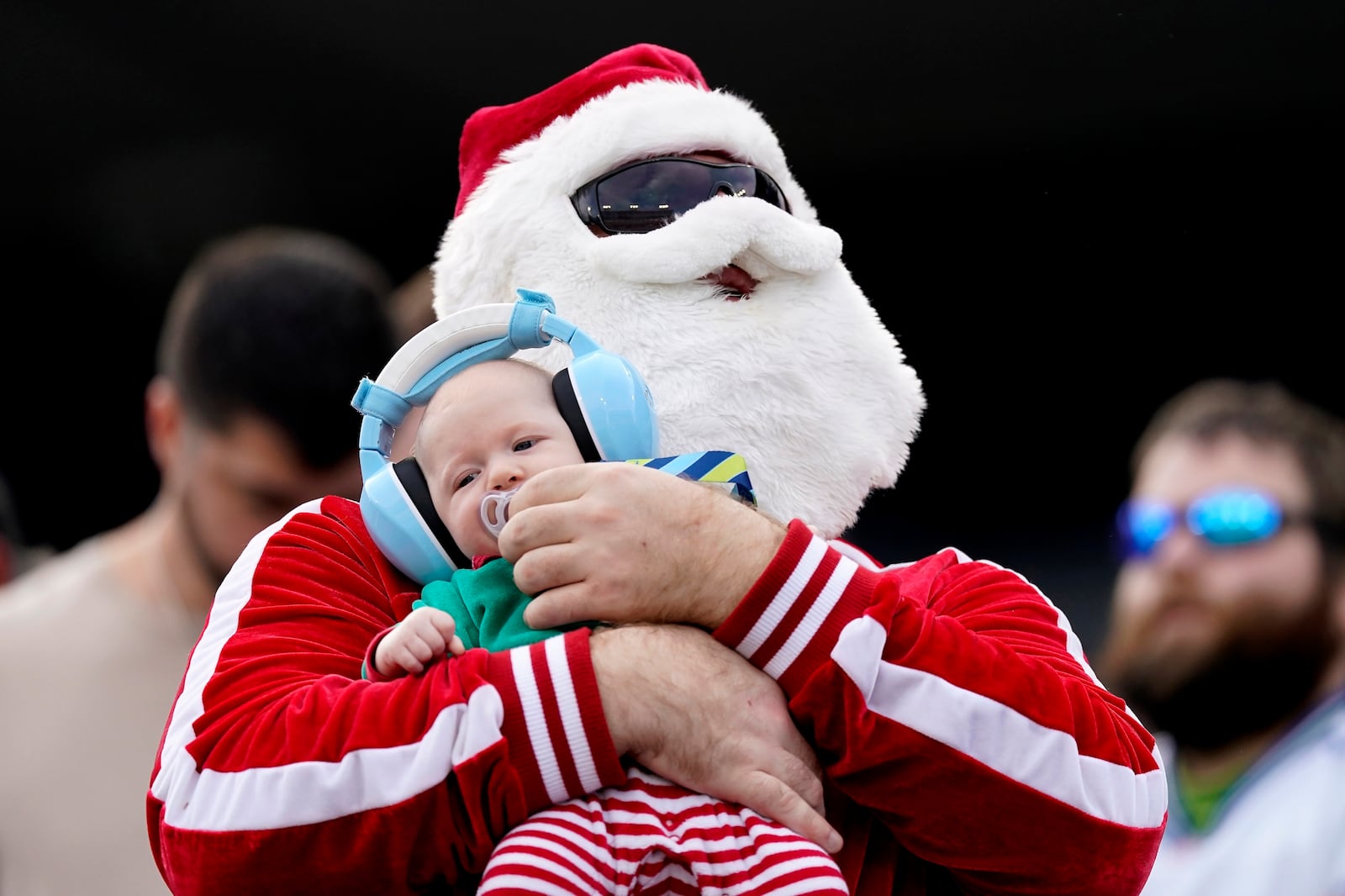 FILE - A fan wearing a Santa Claus beard holds a child during the second half of an NFL football game between the Tennessee Titans and the Seattle Seahawks on Sunday, Dec. 24, 2023, in Nashville, Tenn. (AP Photo/George Walker IV, File)