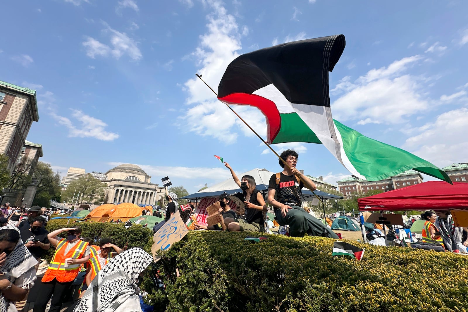 FILE - A demonstrator waves a flag on the Columbia University campus at a pro-Palestinian protest encampment, in New York, April 29, 2024. (AP Photo/Ted Shaffrey, File)