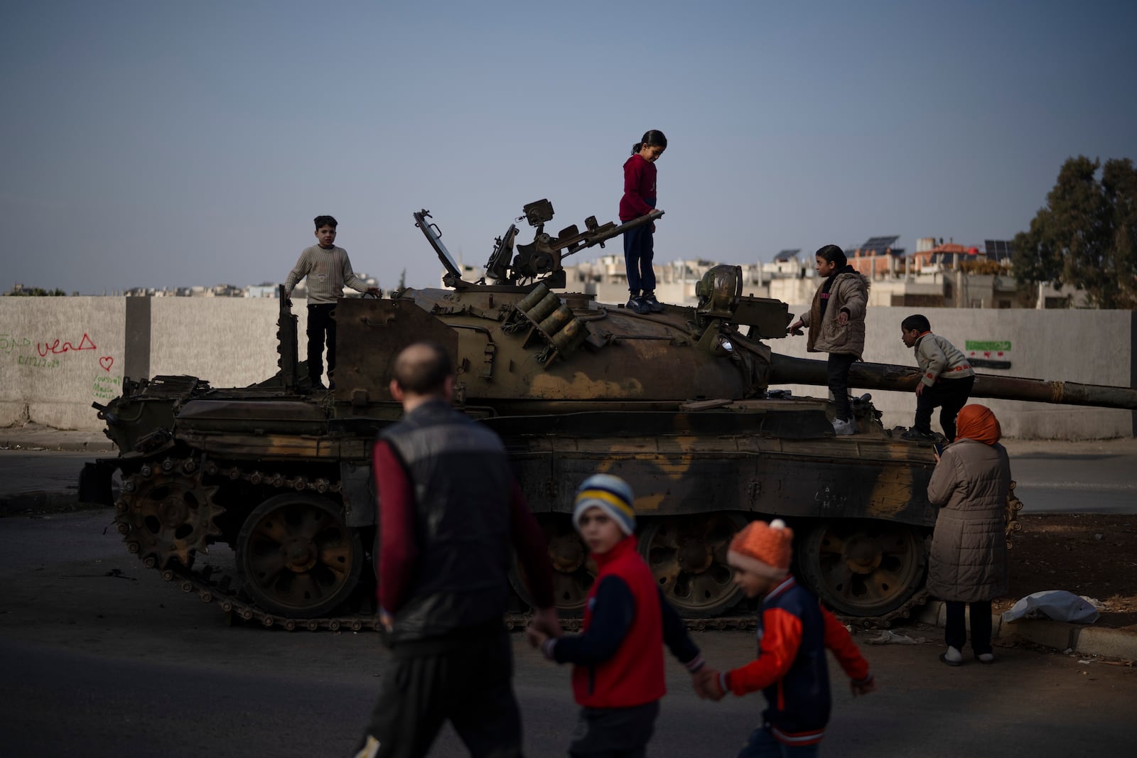 Children on the top of an ousted Syrian government forces tank that was left on a street in an Alawite neighbourhood, in Homs, Syria, Thursday, Dec. 26, 2024. (AP Photo/Leo Correa)