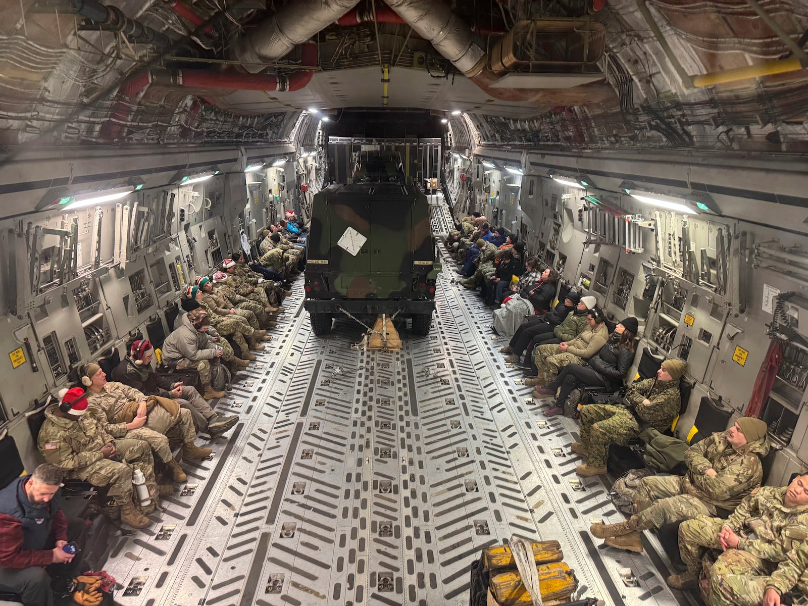 Two Humvees and participants in the Operation Santa program aboard an Alaska Air National Guard C-17 Globemaster III plane also delivering Santa and Mrs. Claus to Yakutat, Alaska, Wednesday, Dec. 18, 2024. (AP Photo/Mark Thiessen).