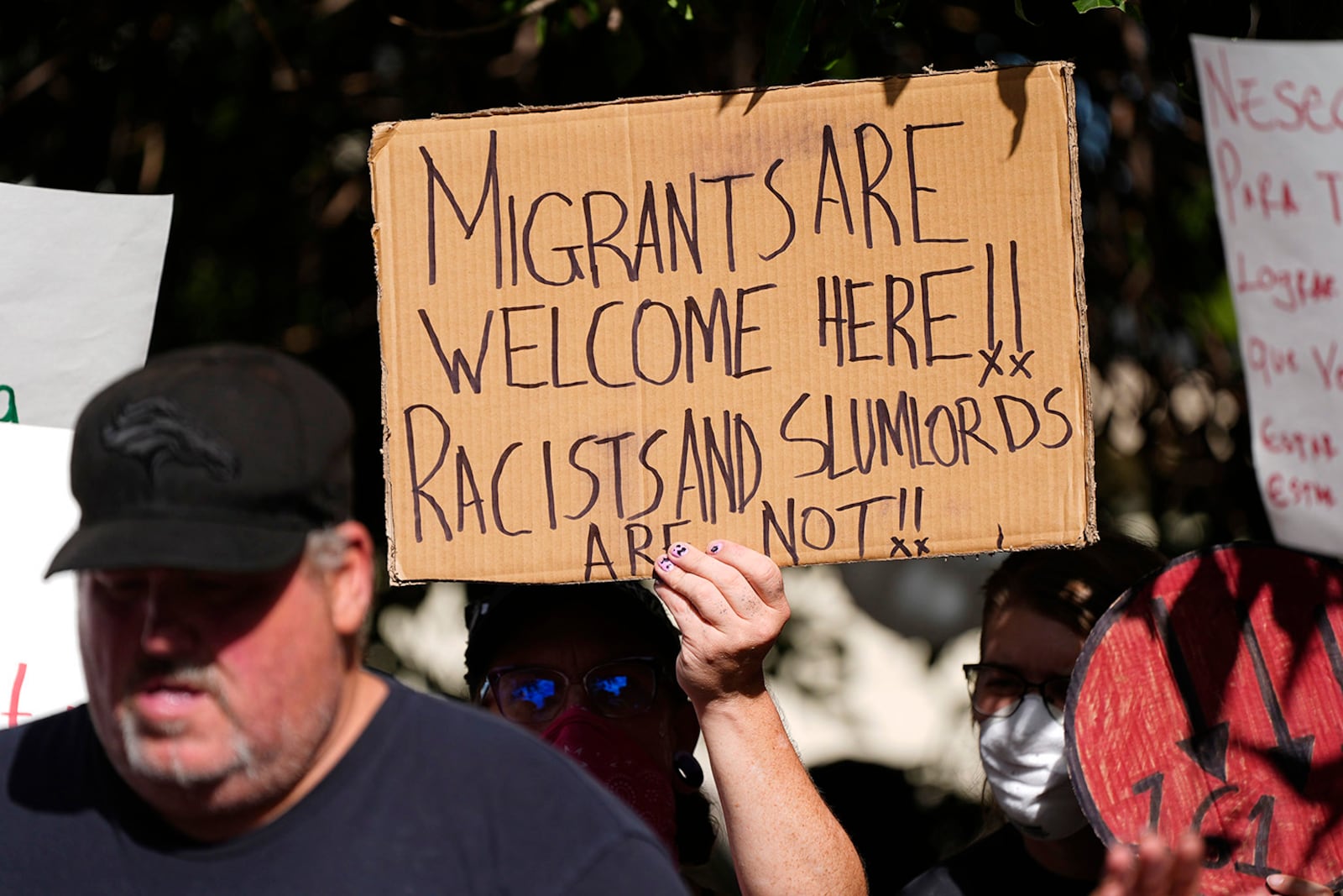 FILE - A person holds up a placard during a rally by the East Colfax Community Collective to address chronic problems in the apartment buildings occupied by people displaced from their home countries in central and South America, Sept. 3, 2024, in Aurora, Colo. (AP Photo/David Zalubowski, File)