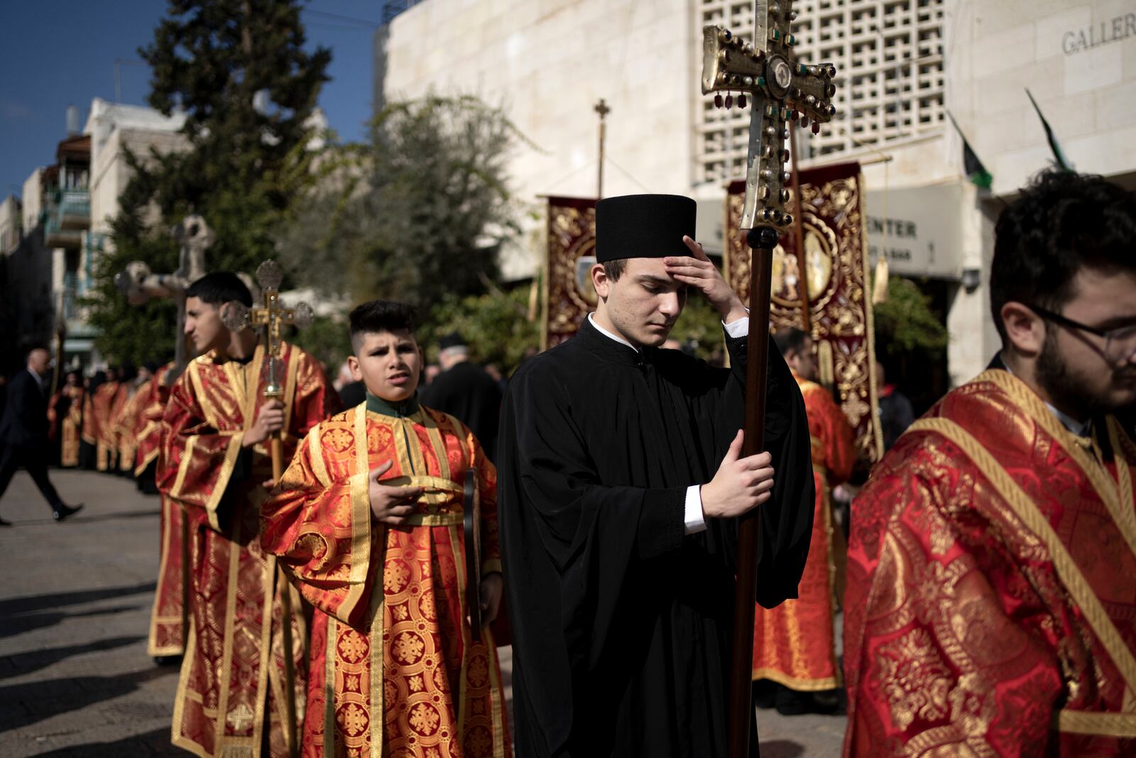 A Greek Orthodox altar boy pauses in Manger Square near the Church of the Nativity, where Christians believe Jesus Christ was born, to walk in a procession ahead of Christmas Eve mass in the West Bank city of Bethlehem, Monday, Jan. 6, 2025. (AP Photo/Maya Alleruzzo)