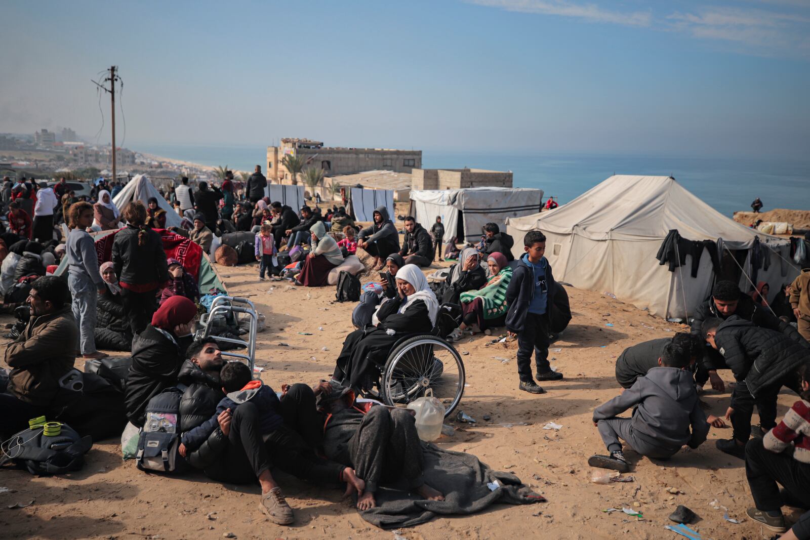 Displaced Palestinians gather with their belongings near a roadblock on the al Rashid Street, as they wait to return to their homes in the northern part of the Gaza Strip, Sunday, Jan. 26, 2025, days after the ceasefire deal between Israel and Hamas came into effect. (AP Photo/ Jehad Alshrafi)