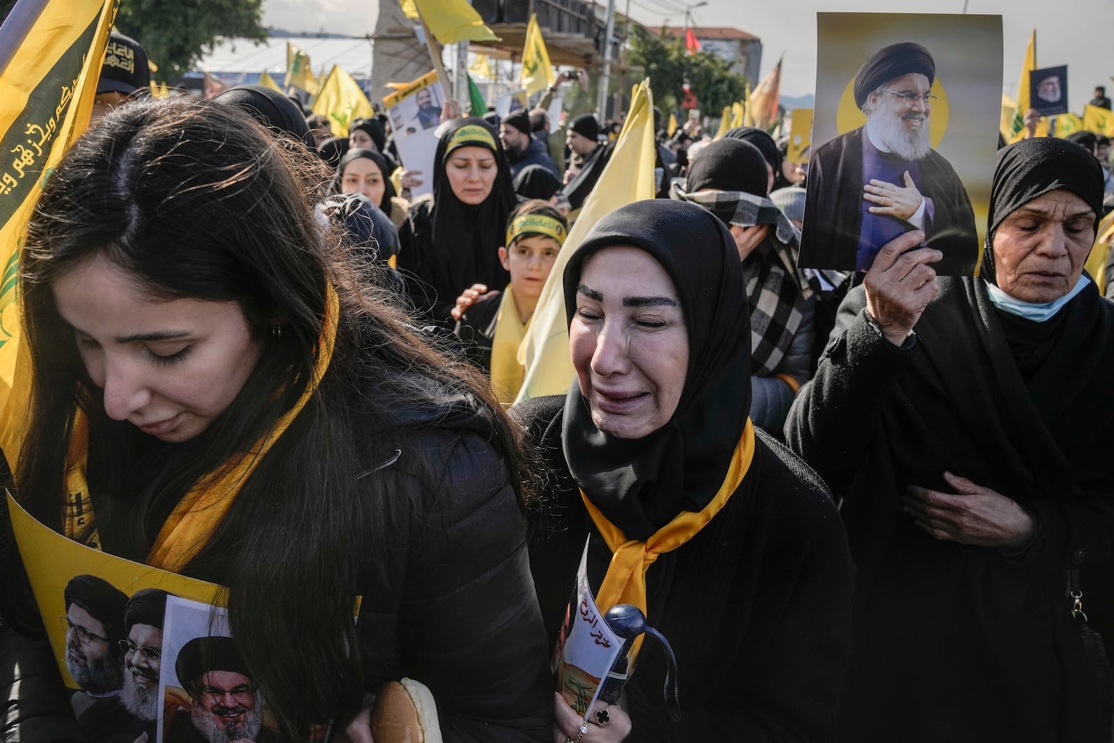 Mourners hold pictures of Hezbollah's former leader Hassan Nasrallah and his cousin and successor Hashem Safieddine as they gather along a highway to attend their funeral procession in Beirut, Lebanon, Sunday Feb. 23, 2025. (AP Photo/Bilal Hussein)