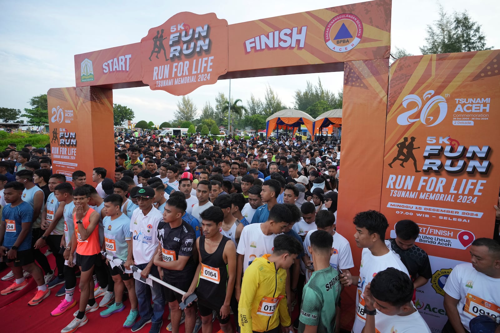 Participants prepare for the start of a 5km running event titled "Run for Life, Tsunami Memorial 2024" held to commemorate the 20th anniversary of the Indian Ocean tsunami, in Banda Aceh, Aceh province, Indonesia, Sunday, Dec. 15, 2024. (AP Photo/Achmad Ibrahim)