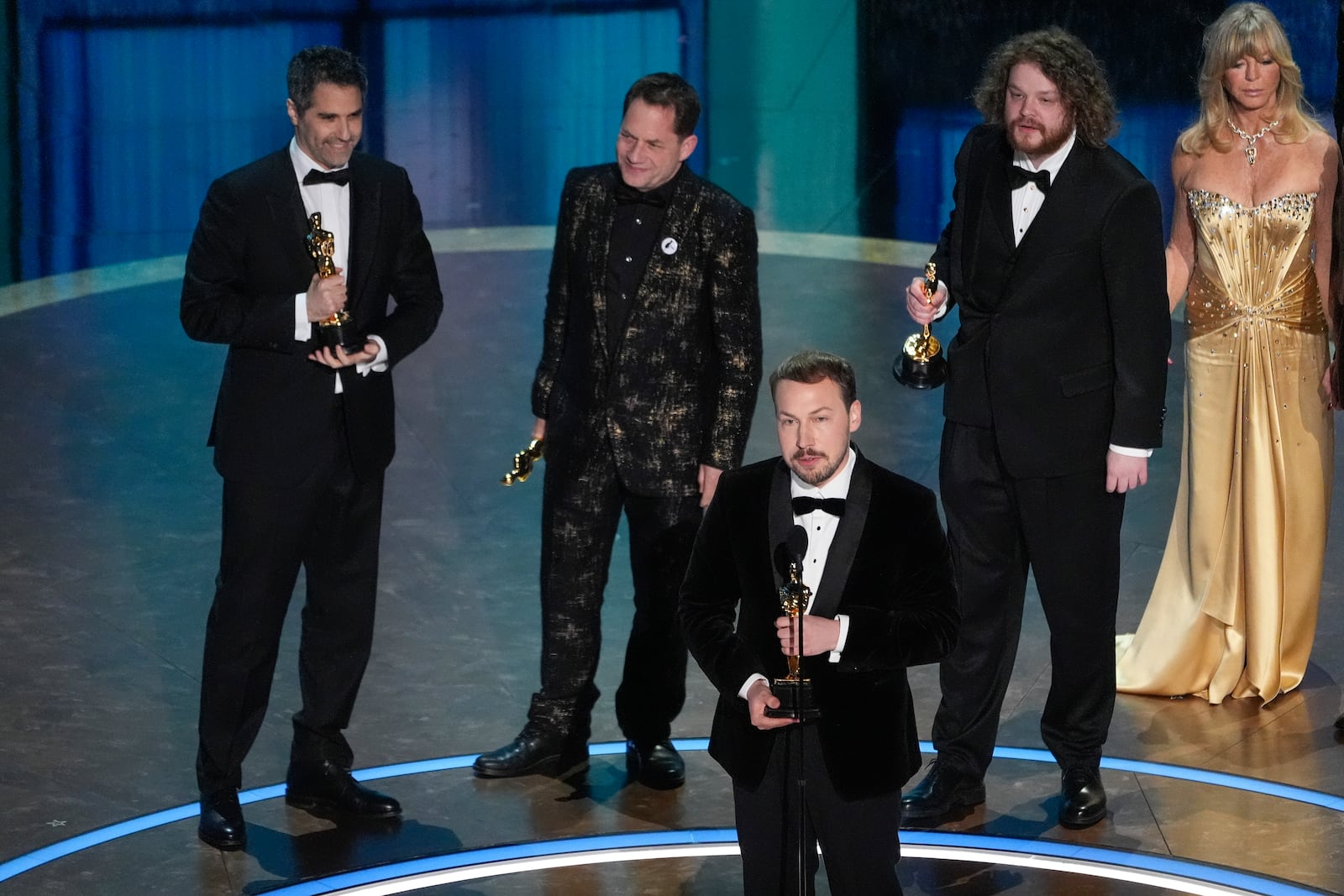 Gregory Zalcman, from left, Ron Dyens, Gints Zilbalodis, center, and Matiss Kaza accept the award for best animated feature film for "Flow" during the Oscars on Sunday, March 2, 2025, at the Dolby Theatre in Los Angeles. Goldie Hawn looks on from right. (AP Photo/Chris Pizzello)