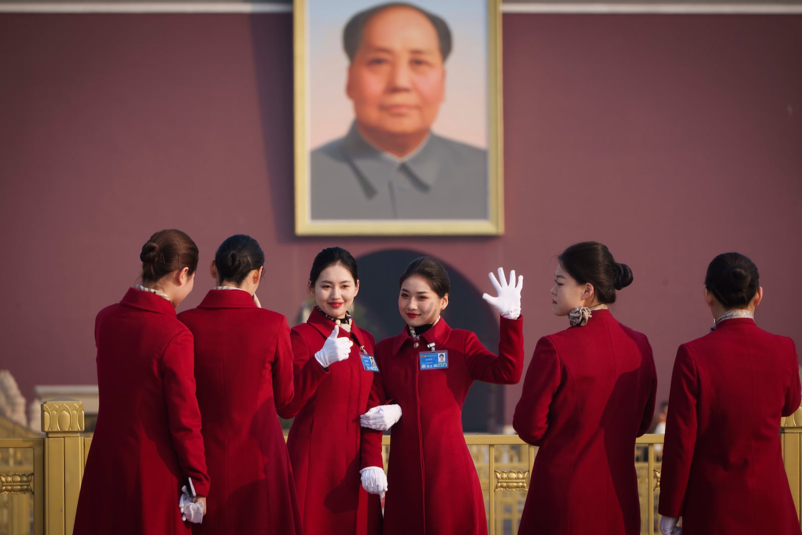 Bus ushers react as they pose for a selfie in front of a portrait of former Chinese leader Mao Zedong at Tiananmen Square during the opening session of the National People's Congress (NPC) at the Great Hall of the People in Beijing, China, Wednesday, March 5, 2025. (AP Photo/Vincent Thian)