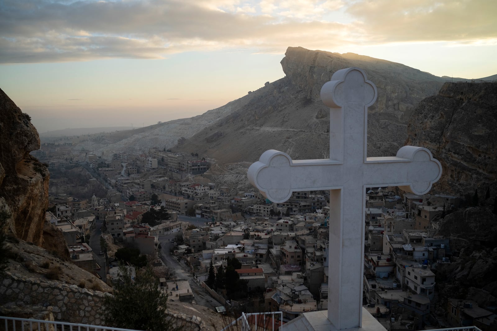 Houses are seen along the mountain as a cross stands over the Greek Orthodox convent Saint Takla on Christmas Eve in Maaloula, some 60 km northern Damascus, Syria, Tuesday, Dec. 24, 2024. (AP Photo/Leo Correa)