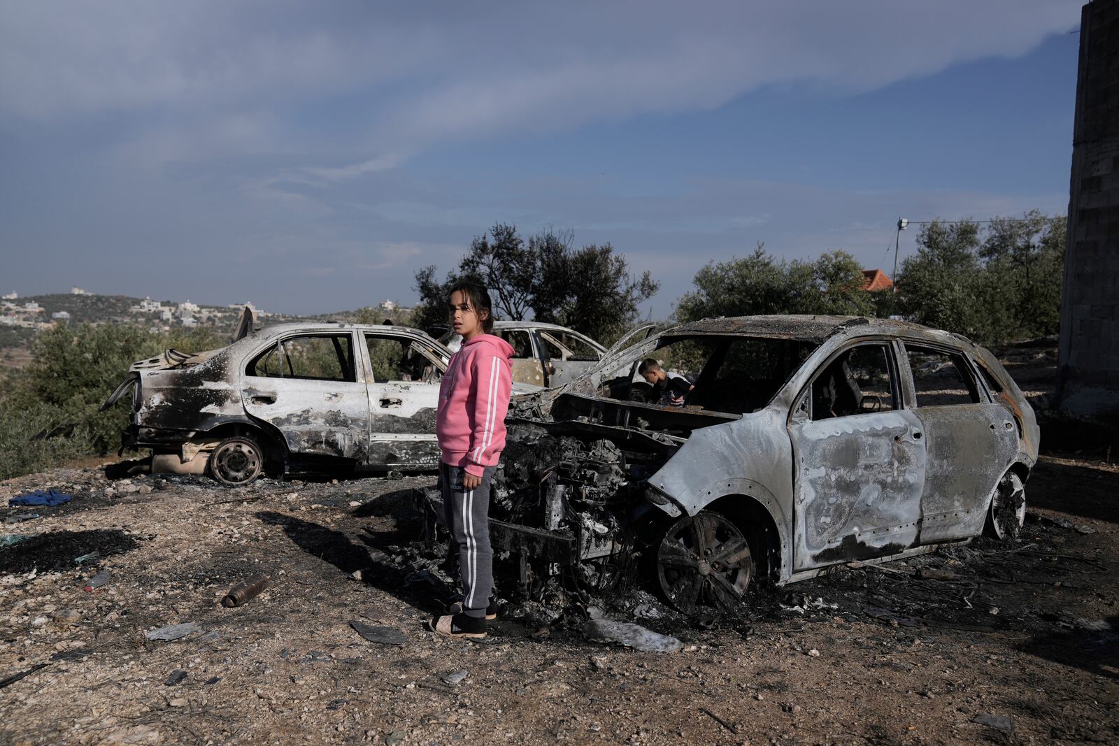 A Palestinian girl looks at a damaged cars following an Israeli airstrike in the West Bank city of Jenin, Thursday, Nov. 21, 2024. (AP Photo/Majdi Mohammed)