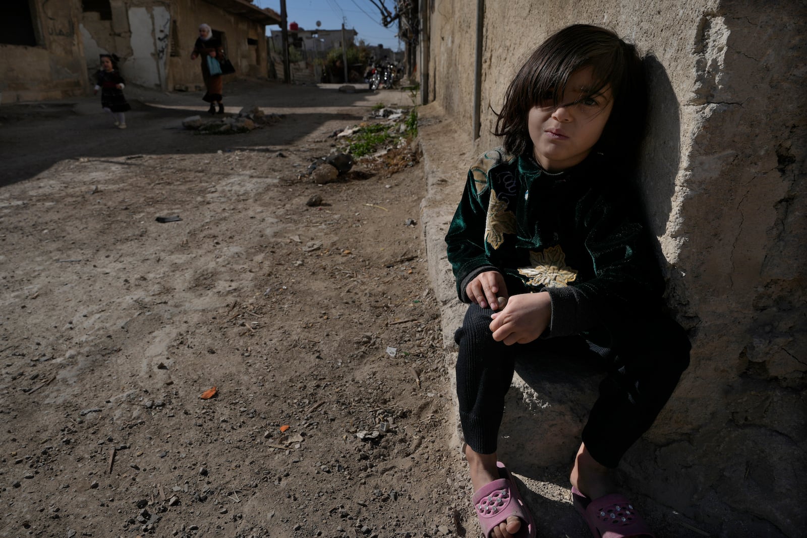 A Syrian girl sits next of her parent house, at an alley that was hit by the sarin struck during a 2013 chemical weapons attack that was blamed on then President Bashar Assad's forces, in Zamalka neighbourhood, on the outskirts of Damascus, Syria, Wednesday, Dec. 25, 2024. (AP Photo/Hussein Malla)