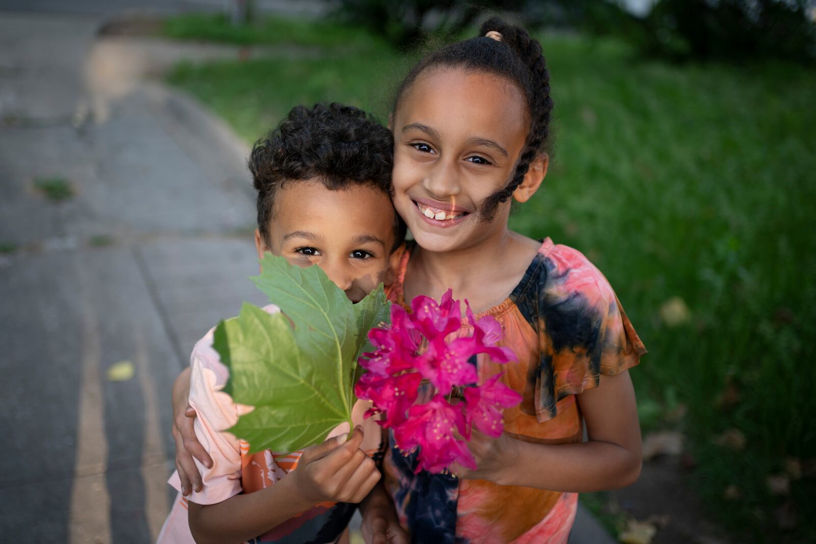 Caydence Manson and her brother, Carter Manson, hold flowers and leaves they found in the garden as they pose for a portrait in Hartford, Conn., on Wednesday, May 25, 2022. The Manson children have dreams - Caydence wants to be an architect, Carter loves sports and hopes to grow up to be an athlete. But for now, they struggle to breathe. (AP Photo/Wong Maye-E)