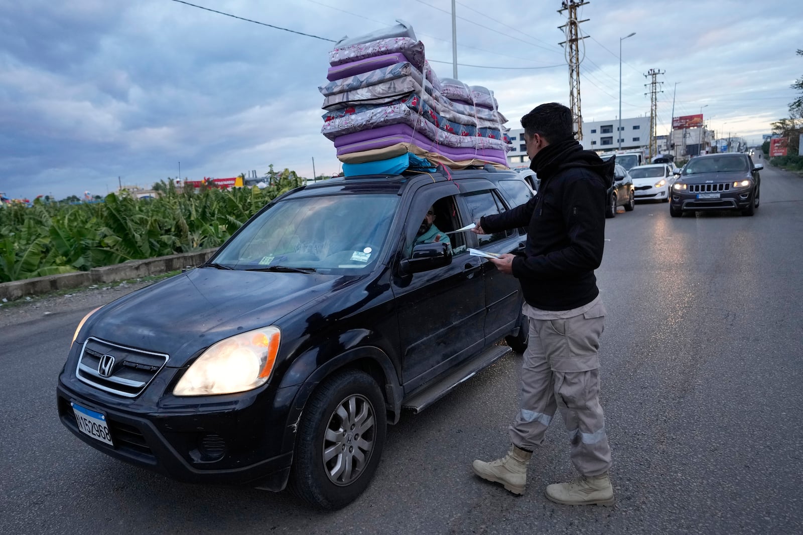 A Civil Defense worker distributes safety fliers to people returning back to their villages after the ceasefire between Hezbollah and Israel began early morning, in Tyre, south Lebanon, Wednesday, Nov. 27, 2024. (AP Photo/Hussein Malla)