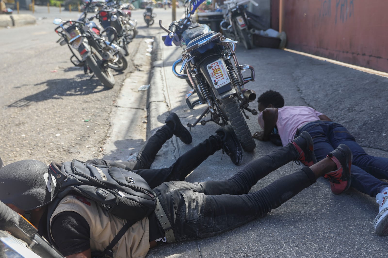 People take cover from the exchange of gunfire between Gangs and police in Port-au-Prince, Haiti, Monday, Nov. 11, 2024. (AP Photo/Odelyn Joseph)