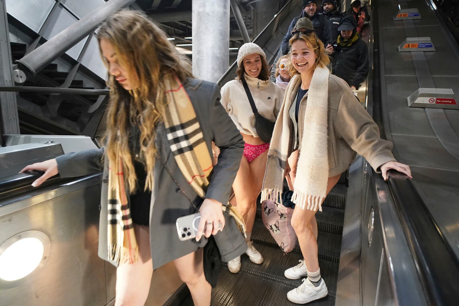 Women on an escalator at Westminster Station as they take part in the annual event "No Trousers Tube Ride" in London, Sunday, Jan. 12, 2025. (AP Photo/Alberto Pezzali)