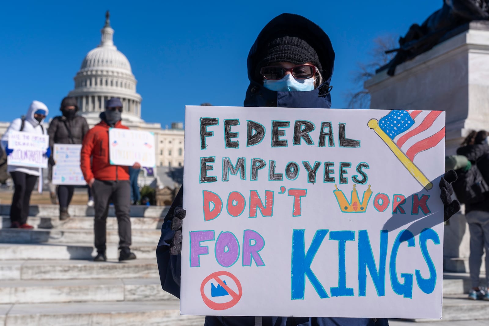 A federal employee, who asked not to use their name for fears over losing their job, protests with a sign saying "Federal Employees Don't Work for Kings" during the "No Kings Day" protest on Presidents Day in Washington, in support of federal workers and against recent actions by President Donald Trump and Elon Musk, Monday, Feb. 17, 2025, by the Capitol in Washington. (AP Photo/Jacquelyn Martin)