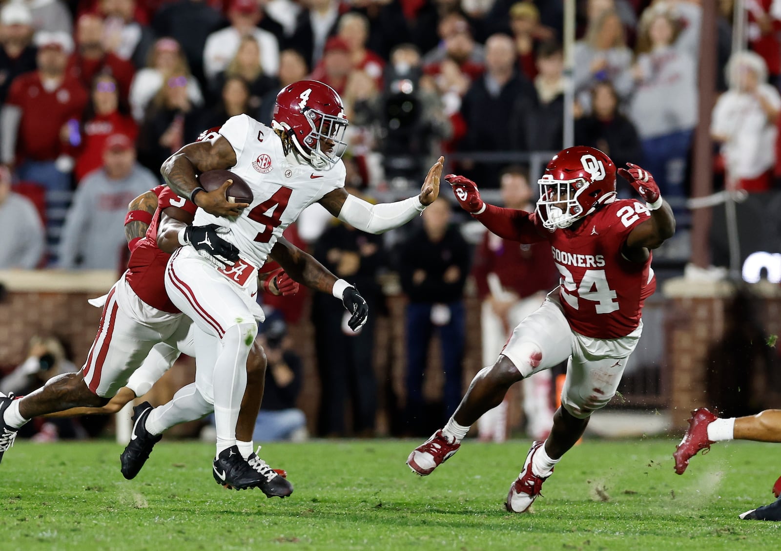 Alabama quarterback Jalen Milroe (4) runs the ball in front of Oklahoma linebacker Samuel Omosigho (24) during the first quarter of a NCAA college football game Saturday, Nov. 23, 2024, in Norman, Okla. (AP Photo/Alonzo Adams)