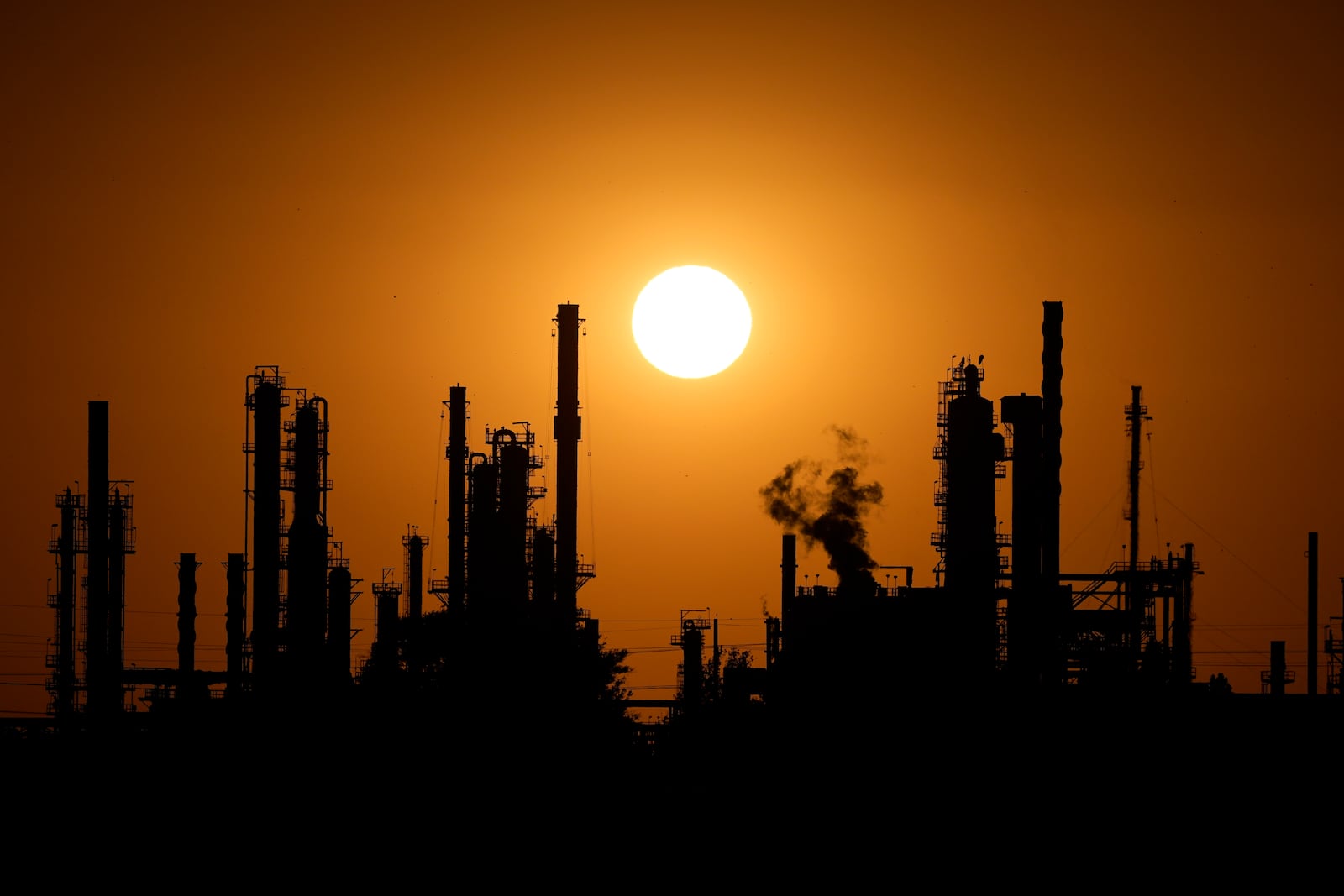 The CHS oil refinery is silhouetted against the setting sun Saturday, Sept. 28, 2024, in McPherson, Kan. (AP Photo/Charlie Riedel)