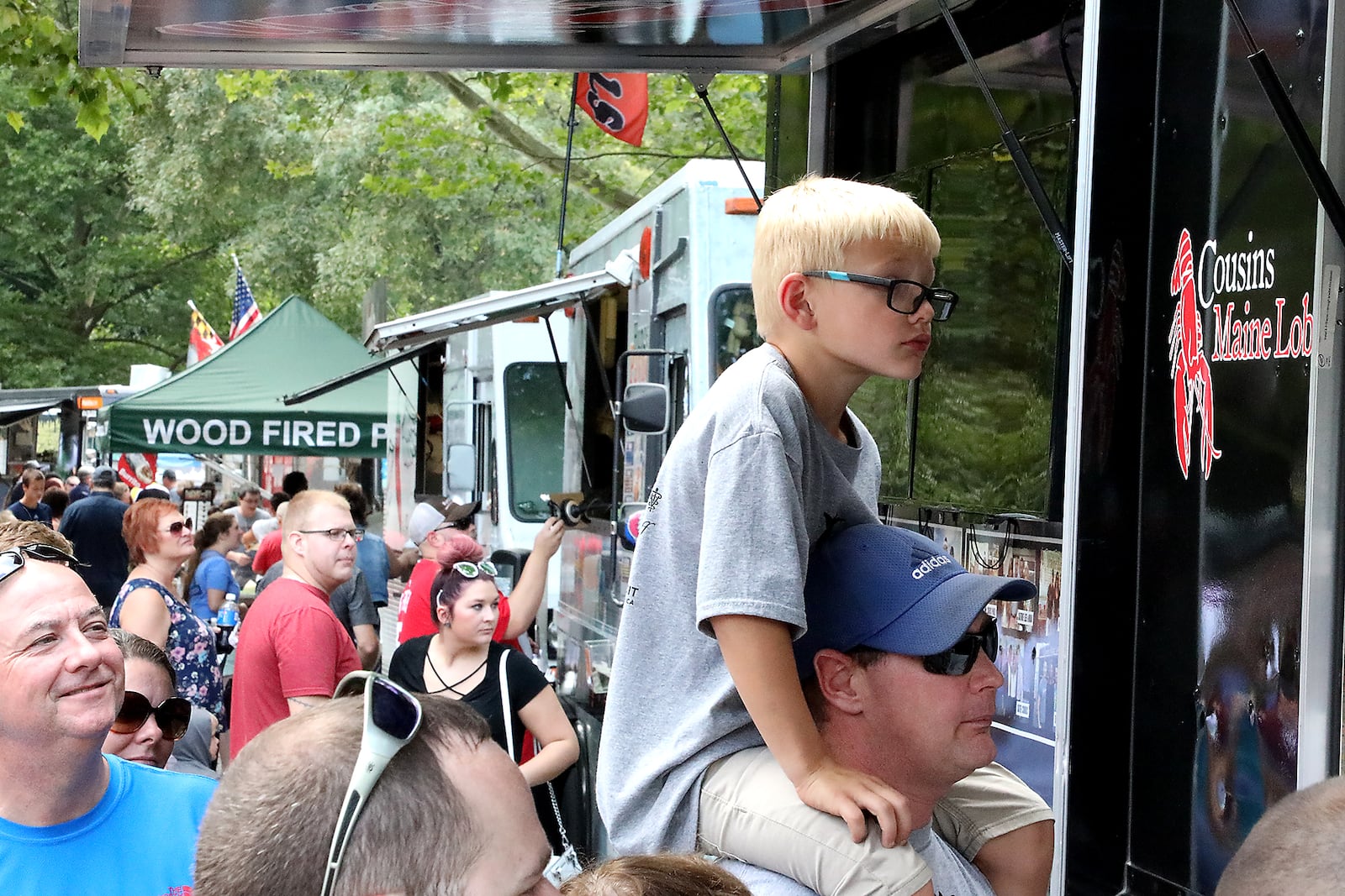 Ross Conrad sits on the shoulders of his father, David, as they wait in line at the Cousins Maine Lobster food truck Saturday during the Springfield Rotary Gourmet Food Truck Competition at Veteran's Park. BILL Lackey/Staff