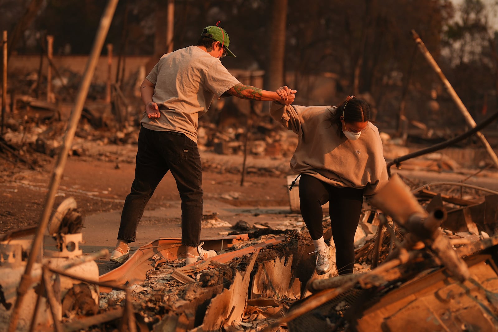 Two people hold hands while sifting through a fire-ravage property in the aftermath of the Eaton Fire Thursday, Jan. 9, 2025 in Altadena, Calif. (AP Photo/Eric Thayer)