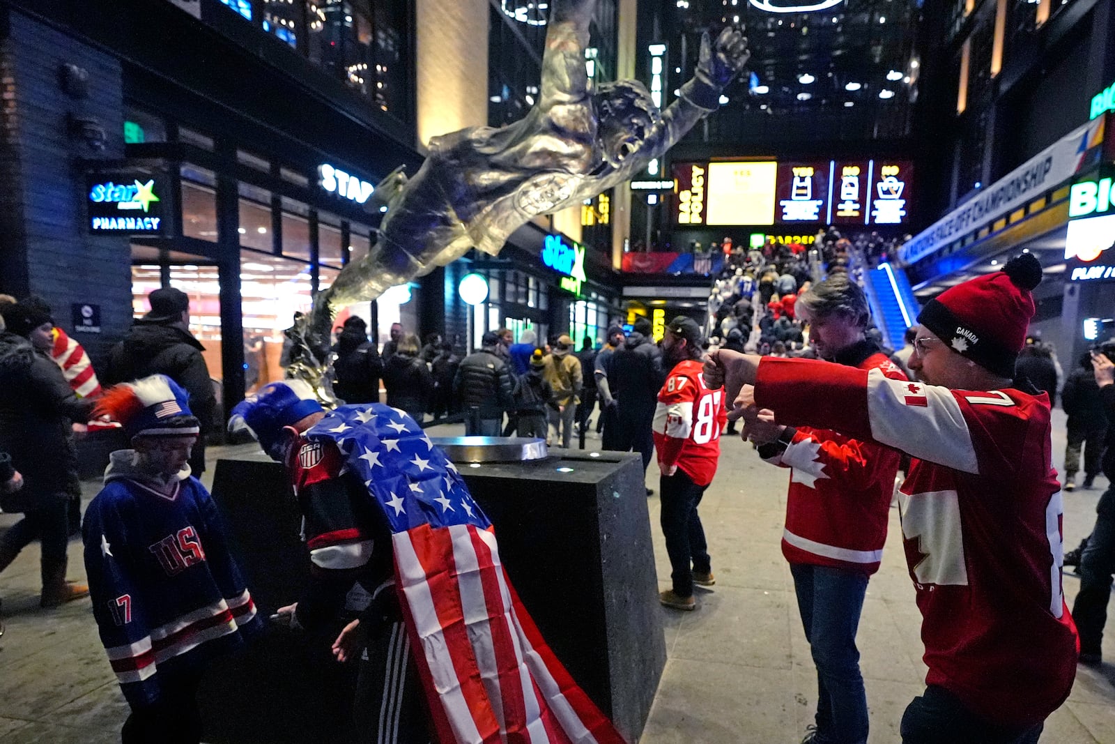 Canada fans, right, taunt United States fans, left, next to the statue of NHL Hall of Famer Bobby Orr prior to the 4 Nations Face-Off championship hockey game, Thursday, Feb. 20, 2025, in Boston. (AP Photo/Charles Krupa)