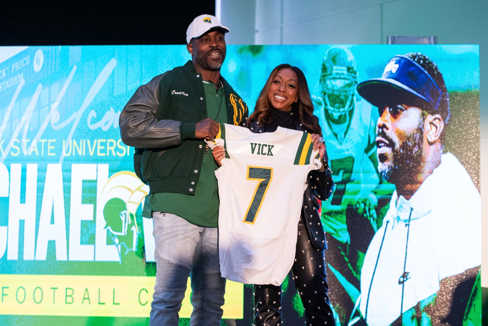 Michael Vick and his wife Kijafa Vick hold up a number seven Norfolk State jersey with his name on it after he was introduced as the next head football coach during a press conference on Monday, Dec. 23, 2024 in Norfolk, Va. (AP Photo/Mike Caudill)