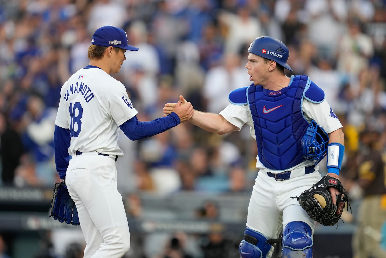 Los Angeles Dodgers starting pitcher Yoshinobu Yamamoto, left, shakes hands with catcher Will Smith after San Diego Padres' Fernando Tatis Jr. grounded into a double play during the third inning in Game 5 of a baseball NL Division Series Friday, Oct. 11, 2024, in Los Angeles. (AP Photo/Ashley Landis)