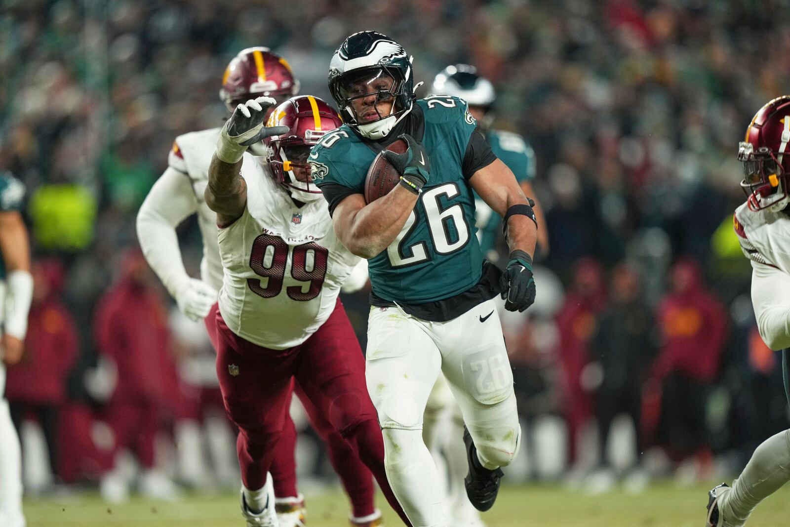 Philadelphia Eagles running back Saquon Barkley (26) runs for a first down as Washington Commanders defensive end Clelin Ferrell (99) defends during the second half of the NFC Championship NFL football game, Sunday, Jan. 26, 2025, in Philadelphia. (AP Photo/Matt Slocum)