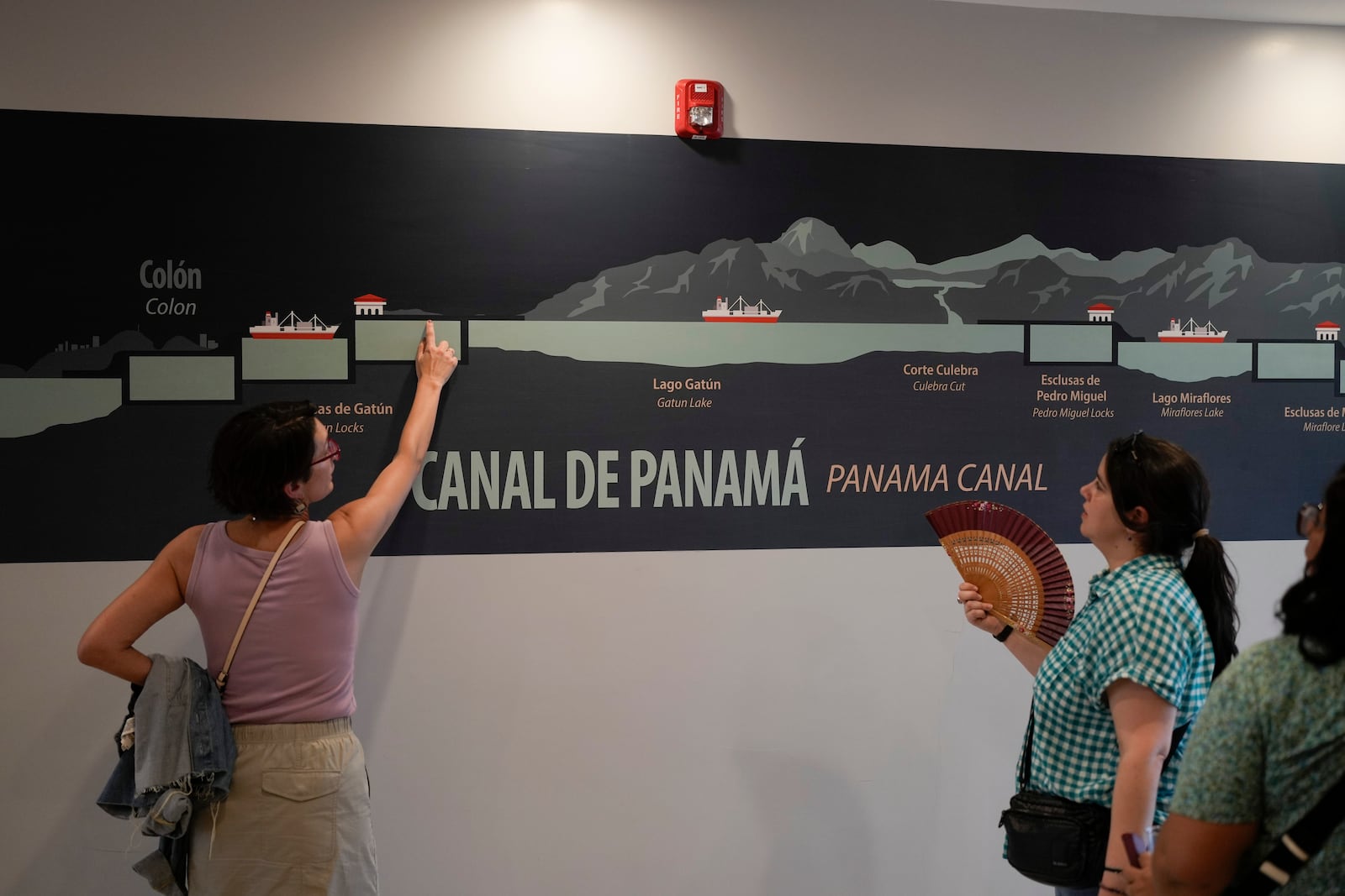 Tourists look at a mural explaining how the Panama Canal works at the Miraflores Locks in Panama City, Monday, Sept. 2, 2024. (AP Photo/Matias Delacroix)