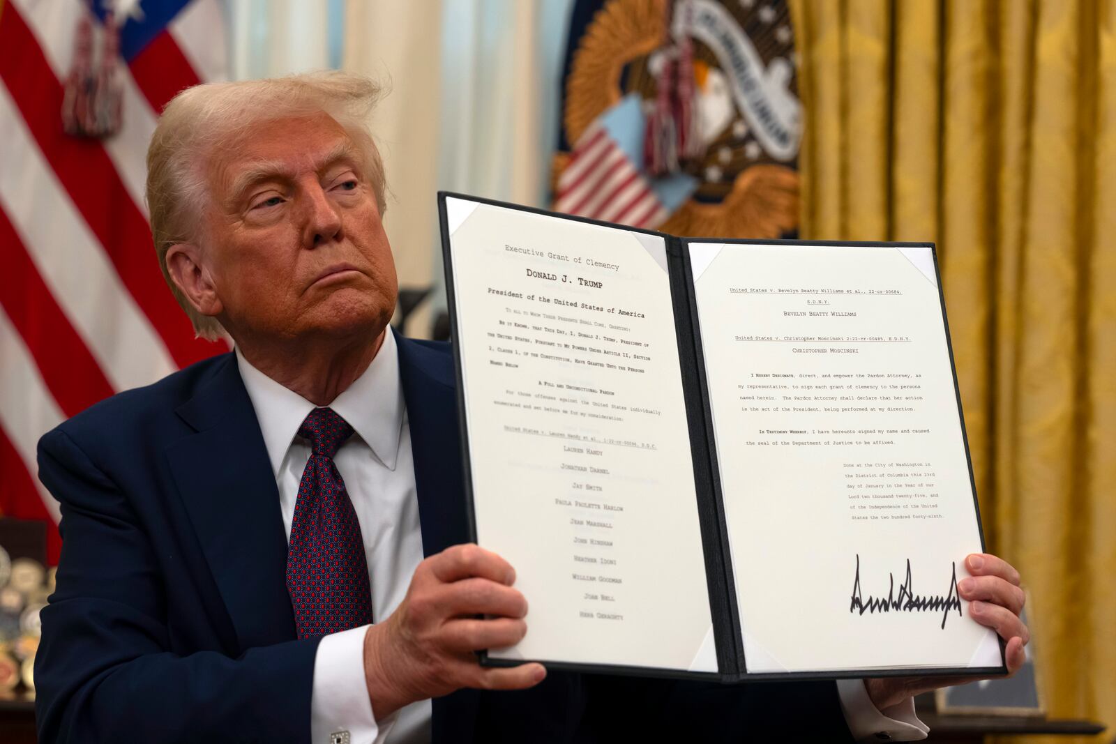 President Donald Trump holds up a signed executive order relating to clemency for anti-abortion protesters as he signs executive orders in the Oval Office of the White House, Thursday, Jan. 23, 2025, in Washington. (AP Photo/Ben Curtis)