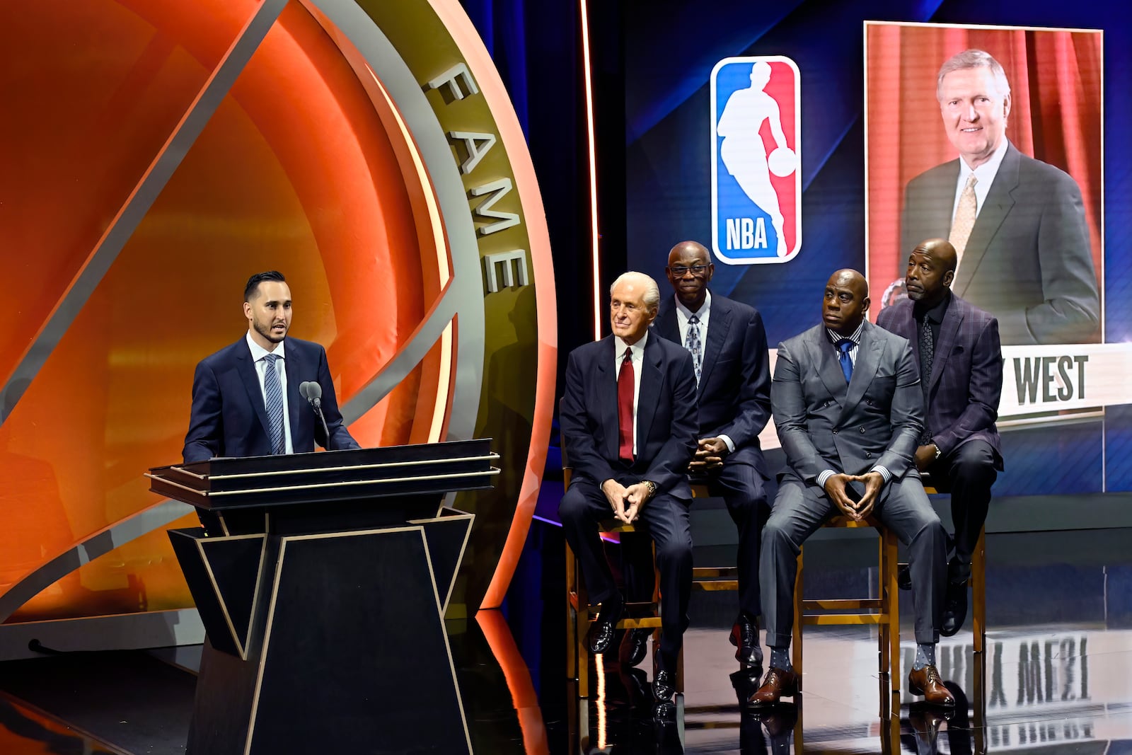 Jonnie West, left, speaks during his late father Jerry West's enshrinement in the Basketball Hall of Fame as, from second from left to right, Pat Riley, Bob McAdoo, Magic Johnson and James Worthy look on Sunday Oct. 13, 2024, in Springfield, Mass. (AP Photo/Jessica Hill)