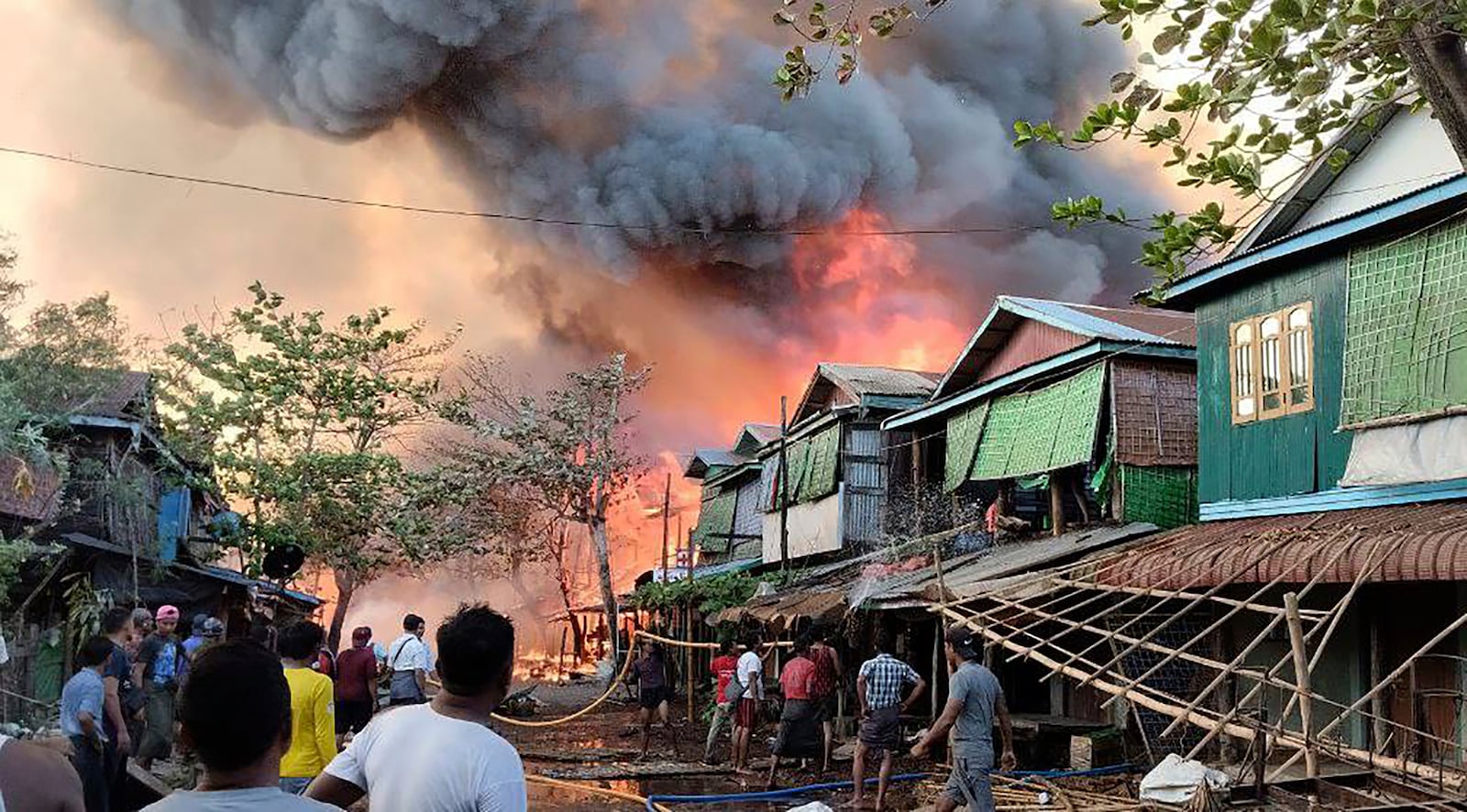 This handout photo provided by the Arakan Army shows people douse flames rising after an airstrike by the ruling military in Kyauk Ni Maw village, in Ramree township, also pronounced Yanbye, in Rakhine state, Myanmar, Wednesday, Jan.8, 2025. (The Arakan Army via AP)