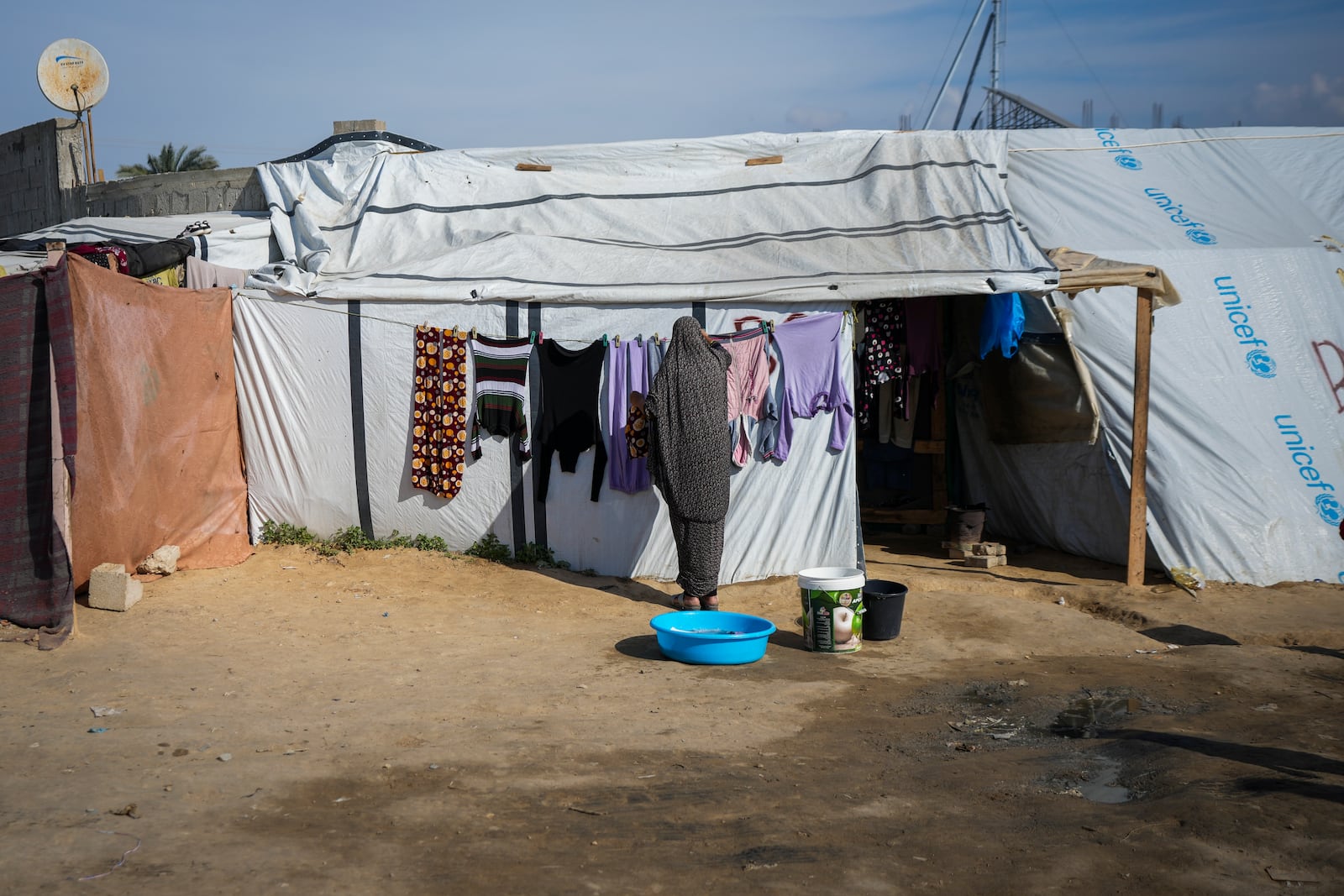 A woman hangs her laundry outside a tent at a camp for displaced Palestinians in Deir al-Balah, central Gaza Strip, Friday Jan. 17, 2025. (AP Photo/Abdel Kareem Hana)