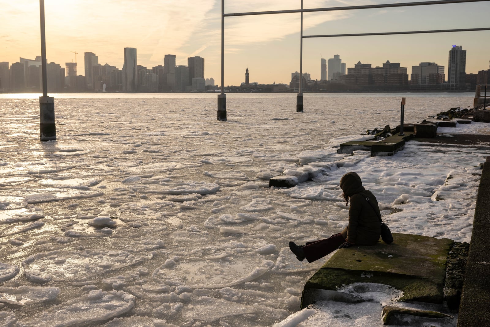 FILE - A person sits on the pier as ice floats on the Hudson River, Jan. 23, 2025, in New York. (AP Photo/Yuki Iwamura, File)