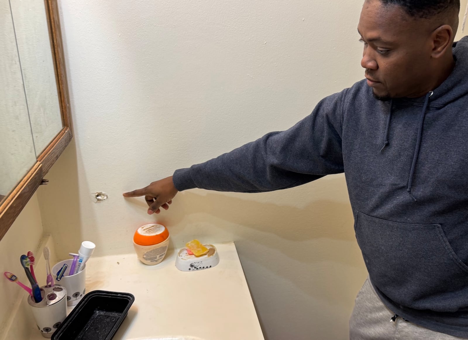 Rosny Petit shows the hole in the wall of his bathroom where one of several bullets entered his house on Southern Avenue Tuesday, Nov. 26, 2024. BILL LACKEY/STAFF