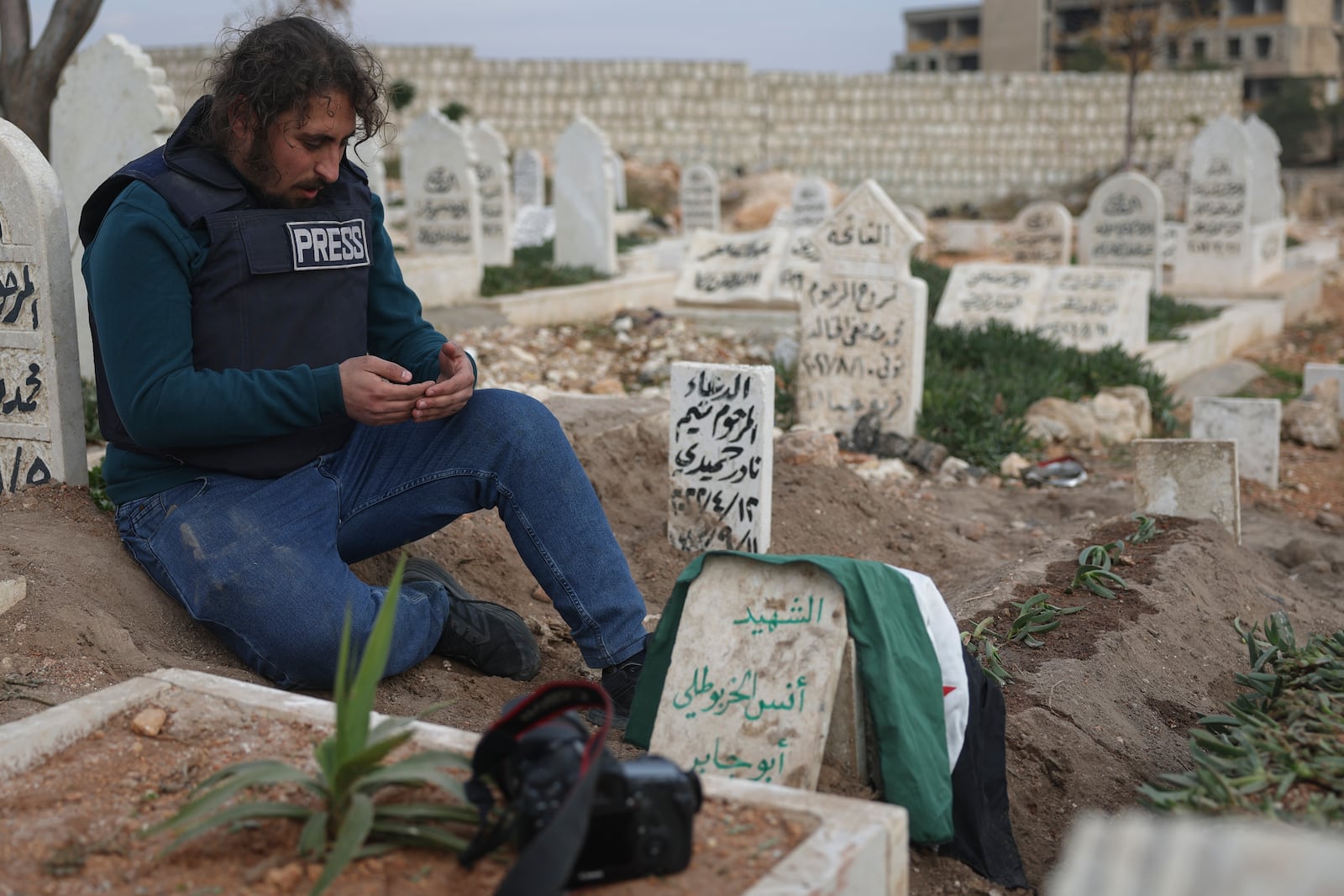 A colleague prays at the grave of Syrian photographer Anas Alkharboutli, 32, following his funeral in Idlib, Syria, on Wednesday, December 4, 2024. Alkharboutli, who worked for the German news agency DPA, was killed in an airstrike near the city of Hama, the agency confirmed.(AP Photo/Ghaith Alsayed)