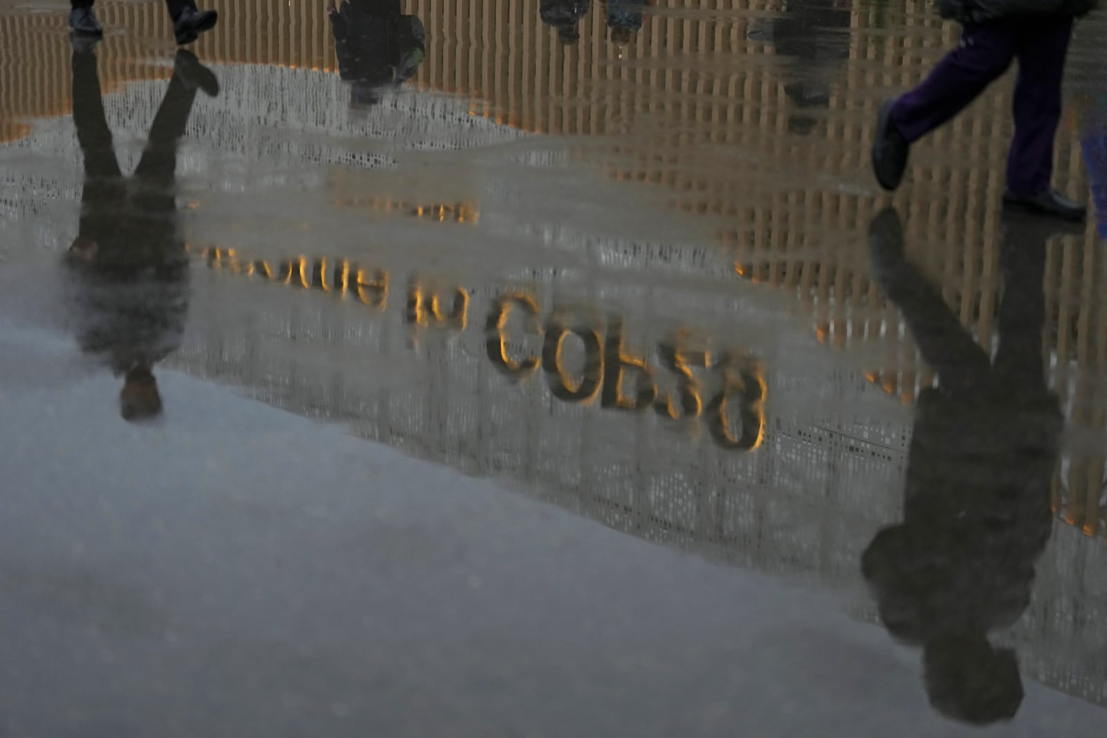 Attendees arrive at the venue as it rains during the COP29 U.N. Climate Summit, Monday, Nov. 18, 2024, in Baku, Azerbaijan. (AP Photo/Peter Dejong)