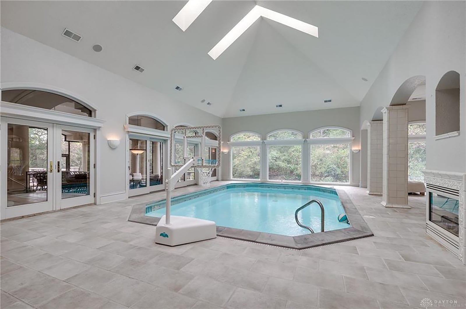 The newer indoor salt water pool is surrounded by windows with views of the wooded lot.