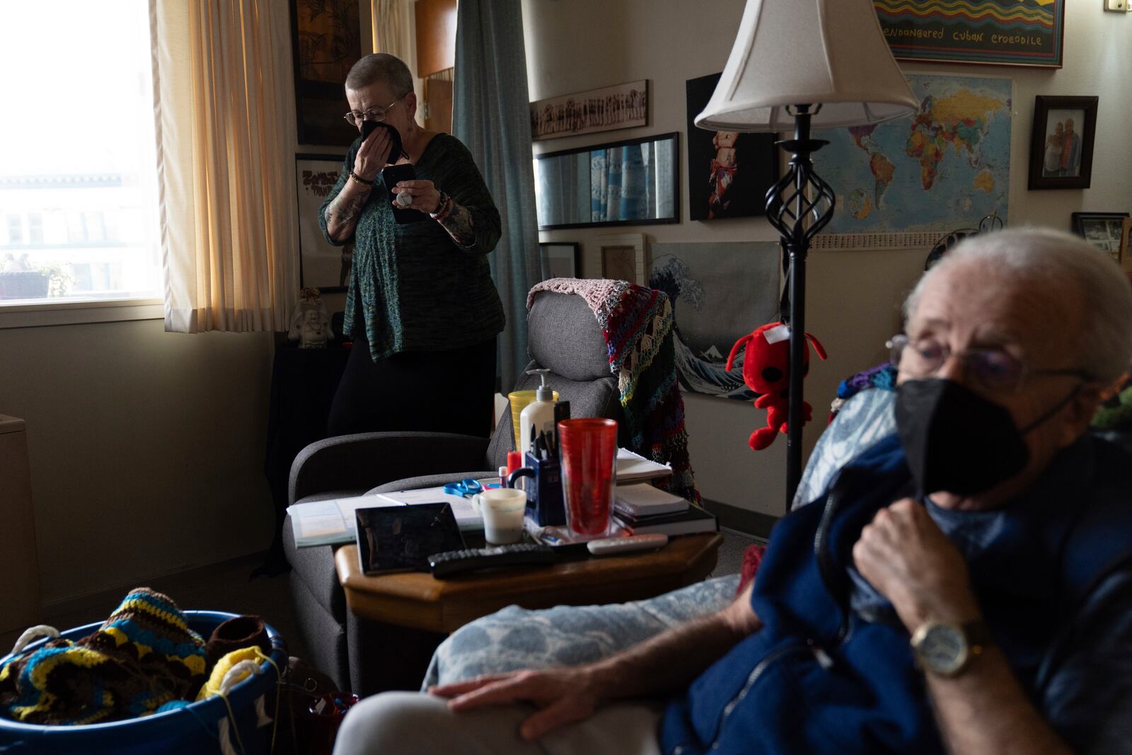 Joan Starr talks on the phone, while Al Hase sits in their living room, at Smith Tower Apartments on Monday, March 10, 2025, in Vancouver, Wash. (AP Photo/Jenny Kane)